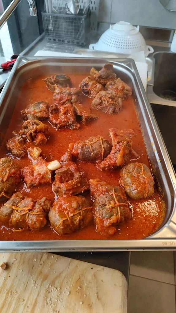 Teglia di polpette al sugo rosso sul piano della cucina, con una pila di focacce lì vicino