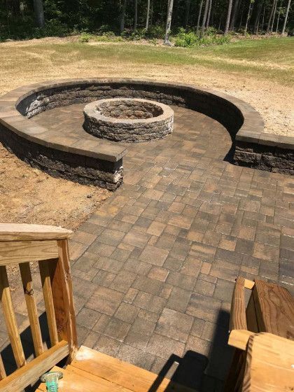Brick patio with fire pit and retaining wall in a yard.