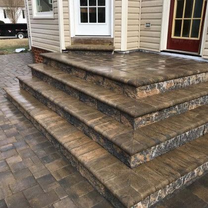 Stone steps leading up to a house entrance. Brown pavers and trim.
