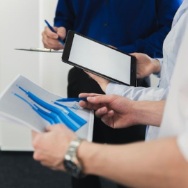People holding a tablet and papers during a meeting