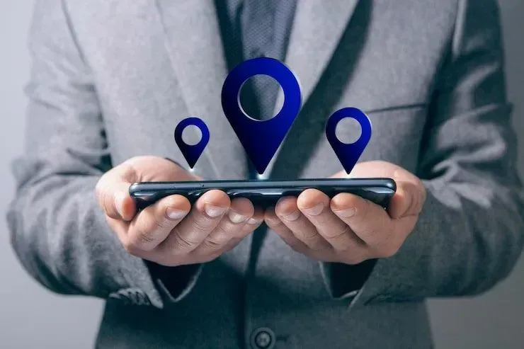 Person holding a smartphone with blue location pins hovering above it