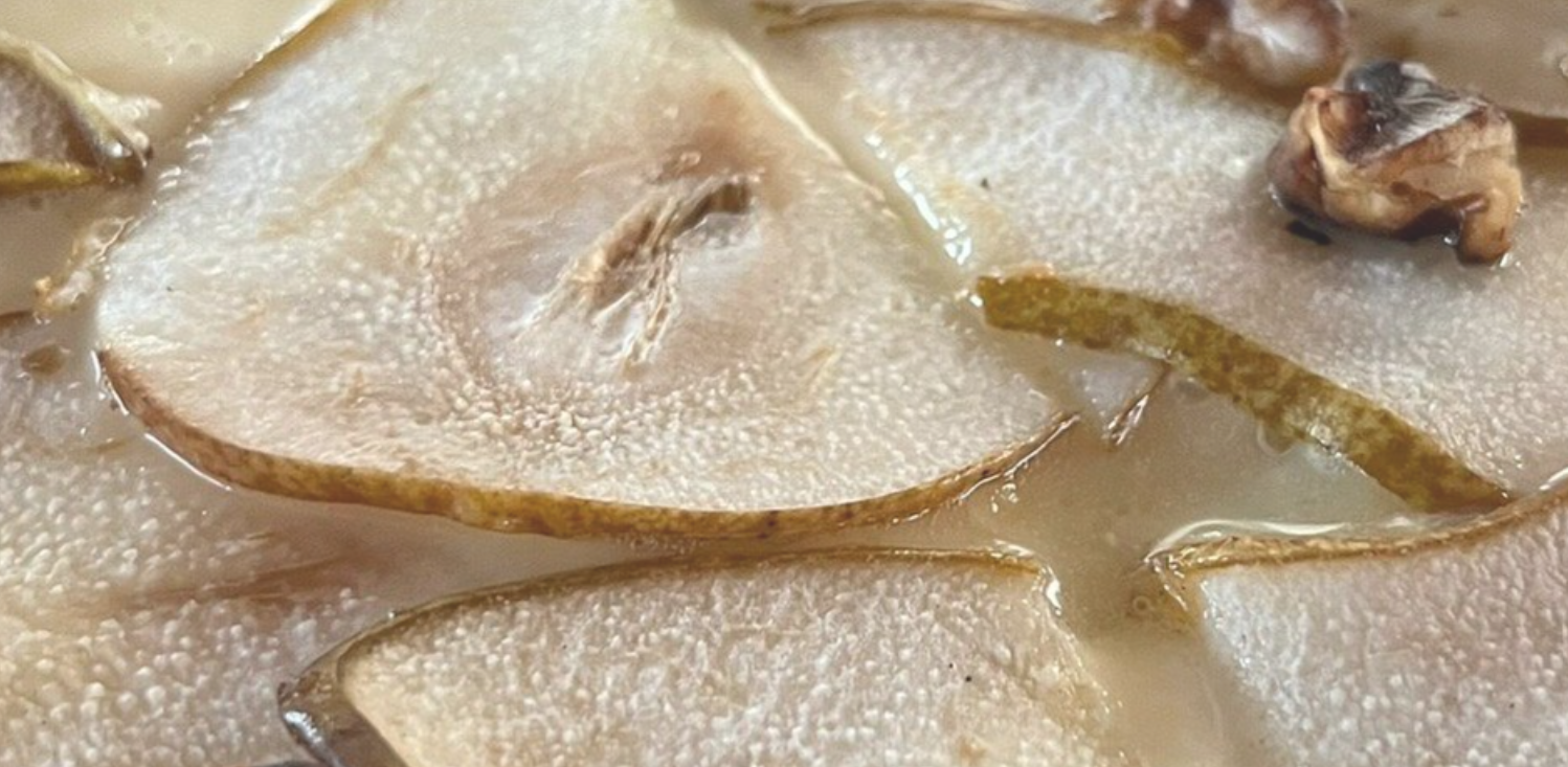 Primo piano di pere a fette che sobbollono in sciroppo o succo in una padella
