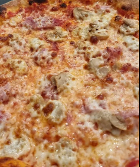 Primo piano di una pizza al formaggio con crosta dorata e condimenti sparsi.