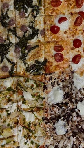 Quattro pizze quadrate con condimenti diversi: pomodorini, olive, erbe aromatiche e cipolle a fette.