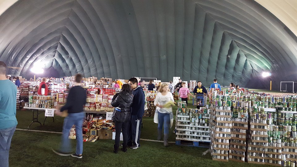 People browsing vendor booths inside a large arched tent at a market or fair.