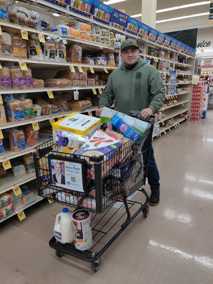 Shopper pushing a loaded cart down a grocery aisle under bright store lights