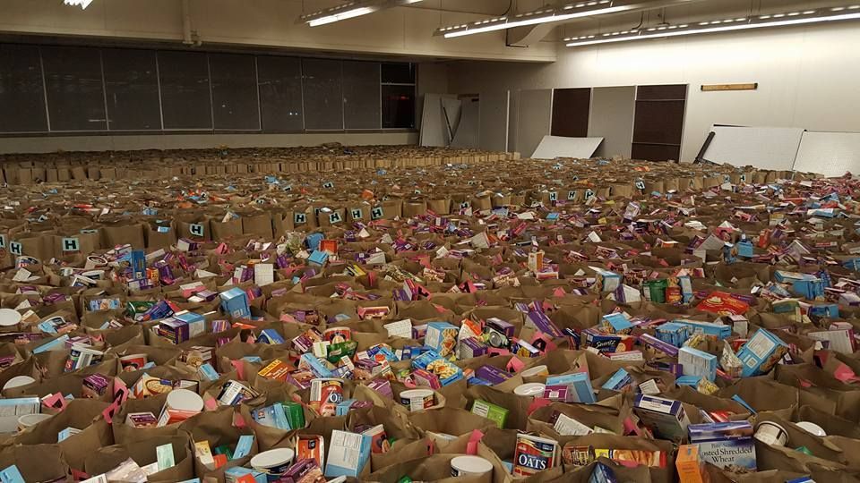 Large indoor hall filled wall-to-wall with stacked, colorful gift packages and toys for donation