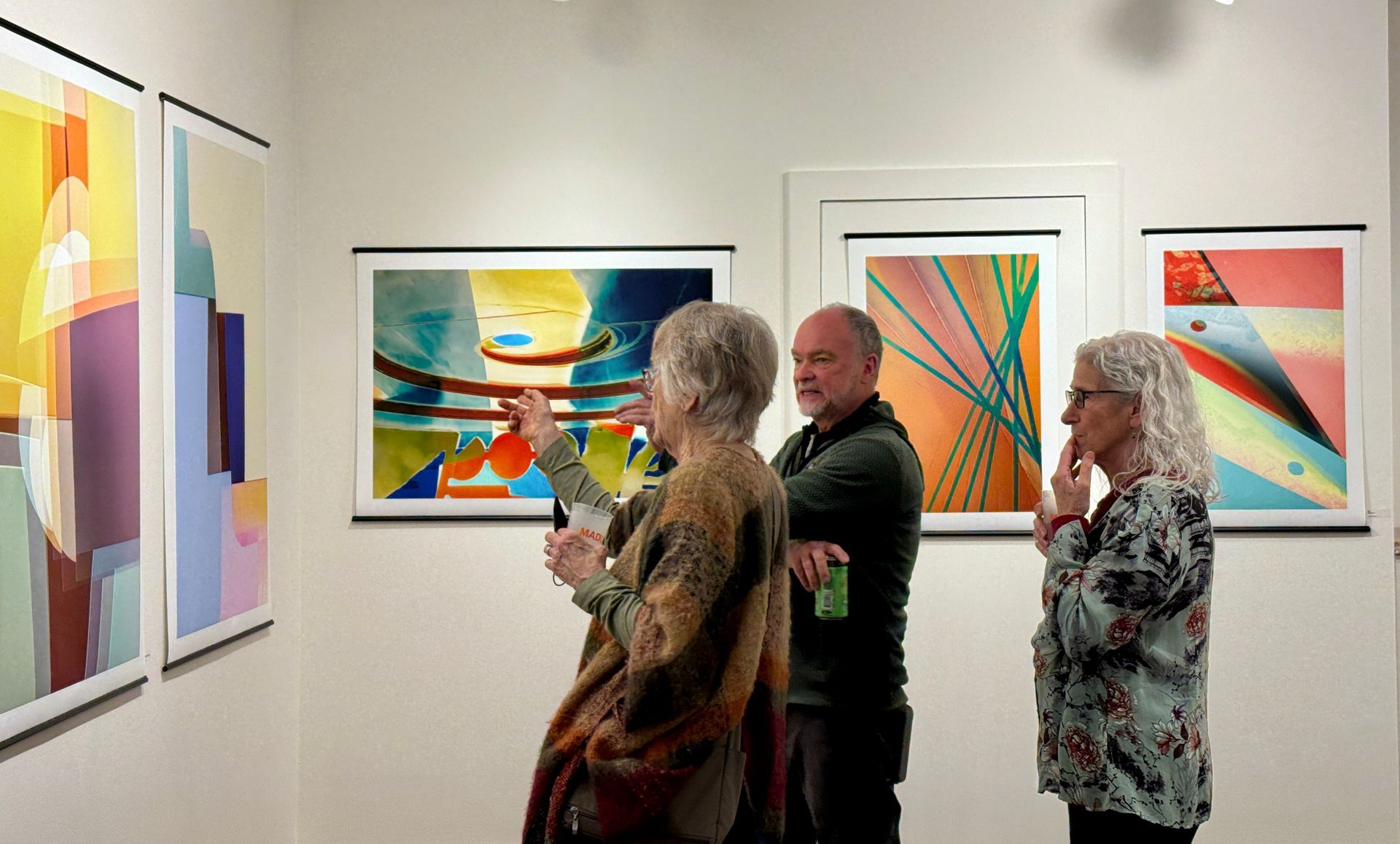 People viewing colorful abstract paintings in a gallery.