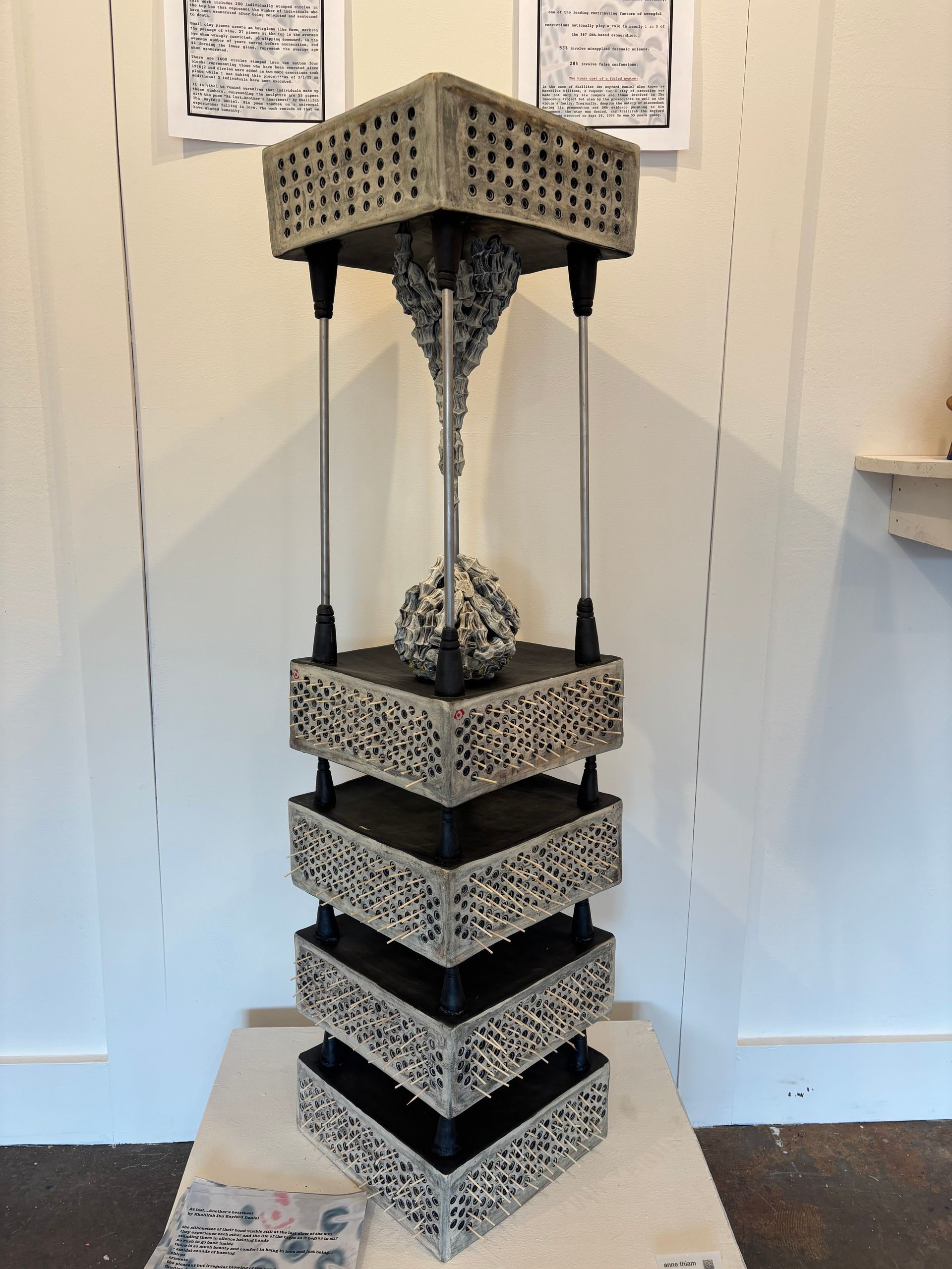 Abstract black-and-white geometric sculpture with stacked square tiers and perforated top and base indoors