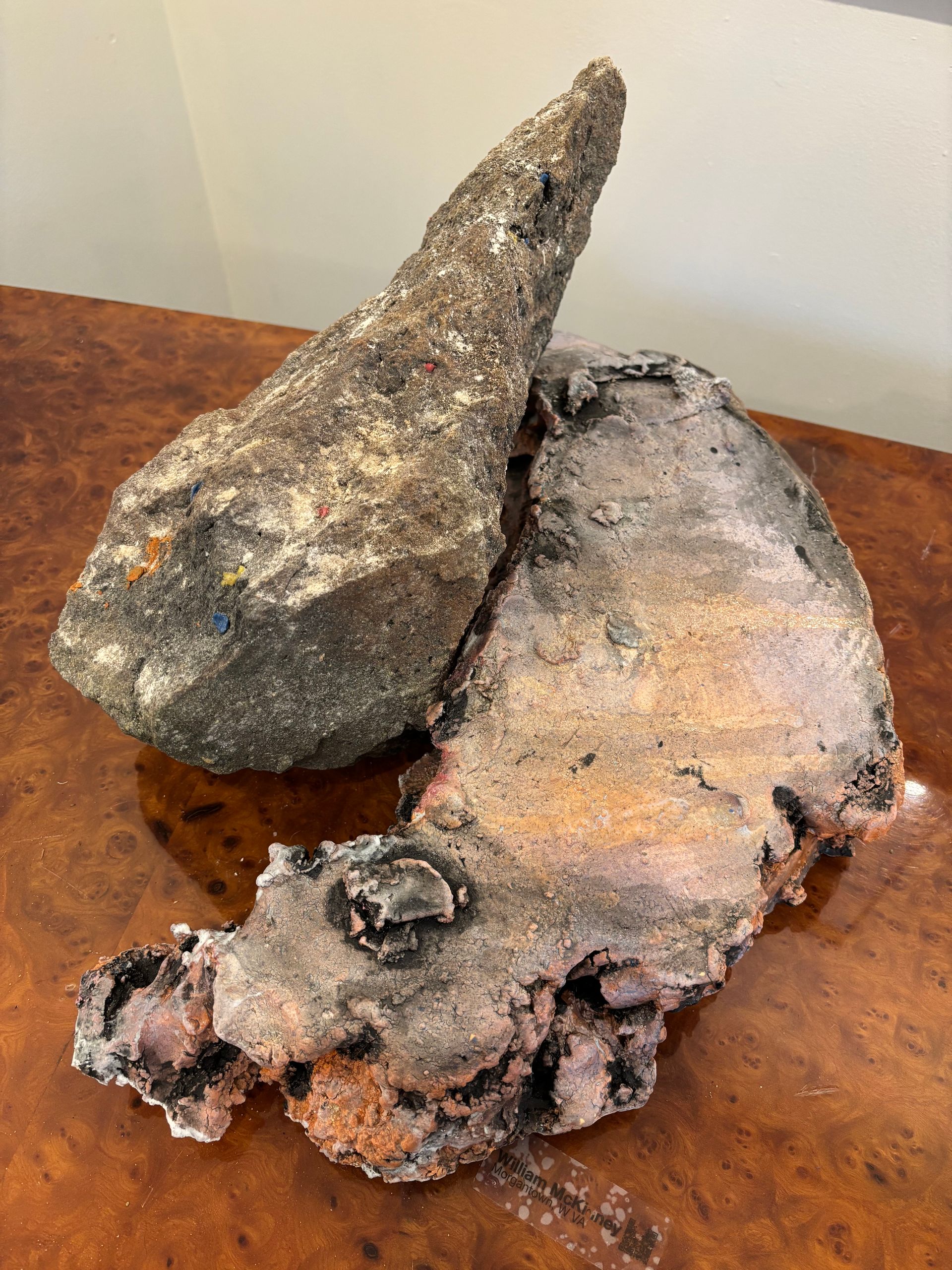 Two rough, dark rock-like objects with orange and gray mineral texture on a wooden surface