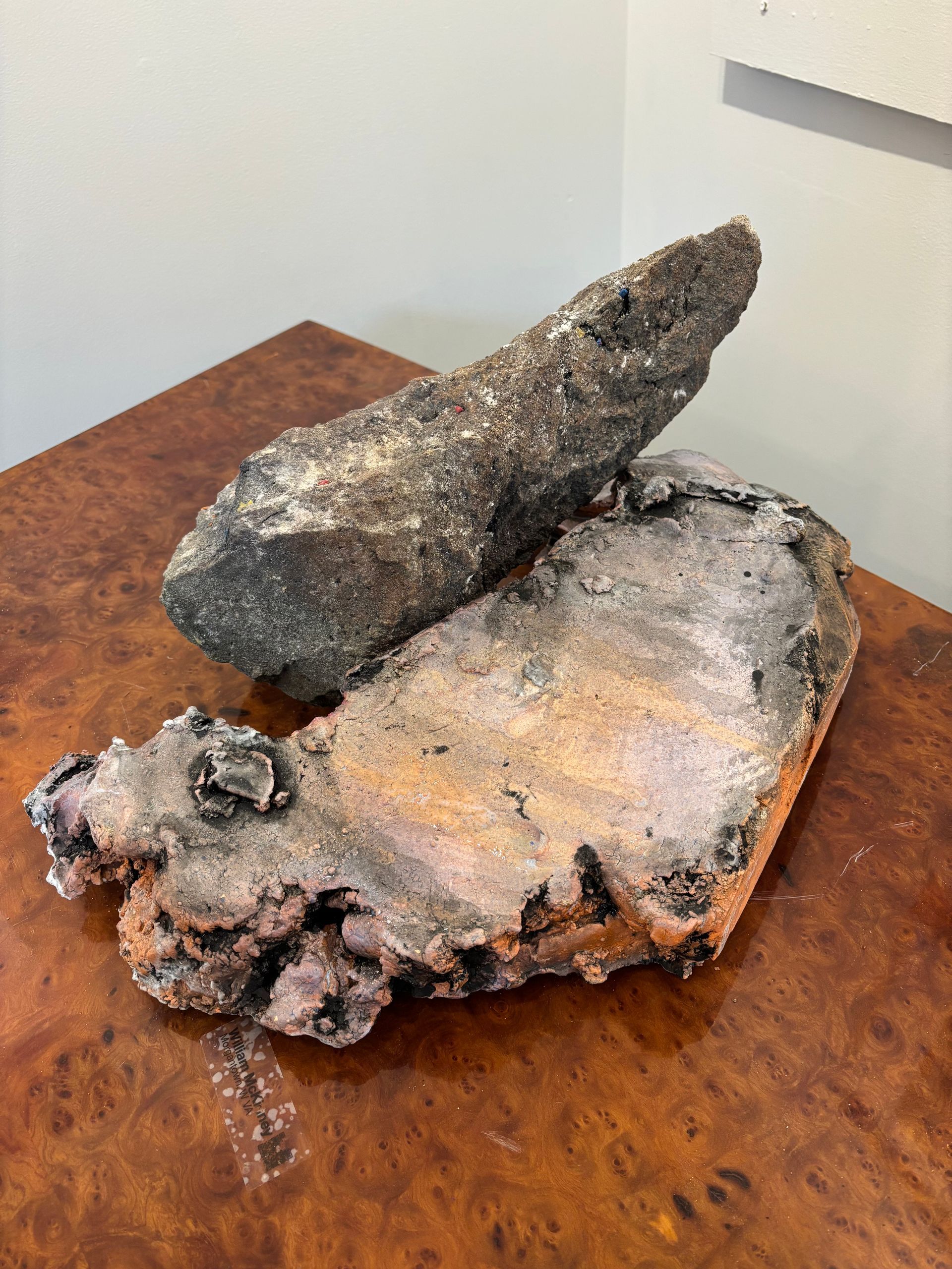 Two rough, dark mineral rocks on a wooden table against a light wall.