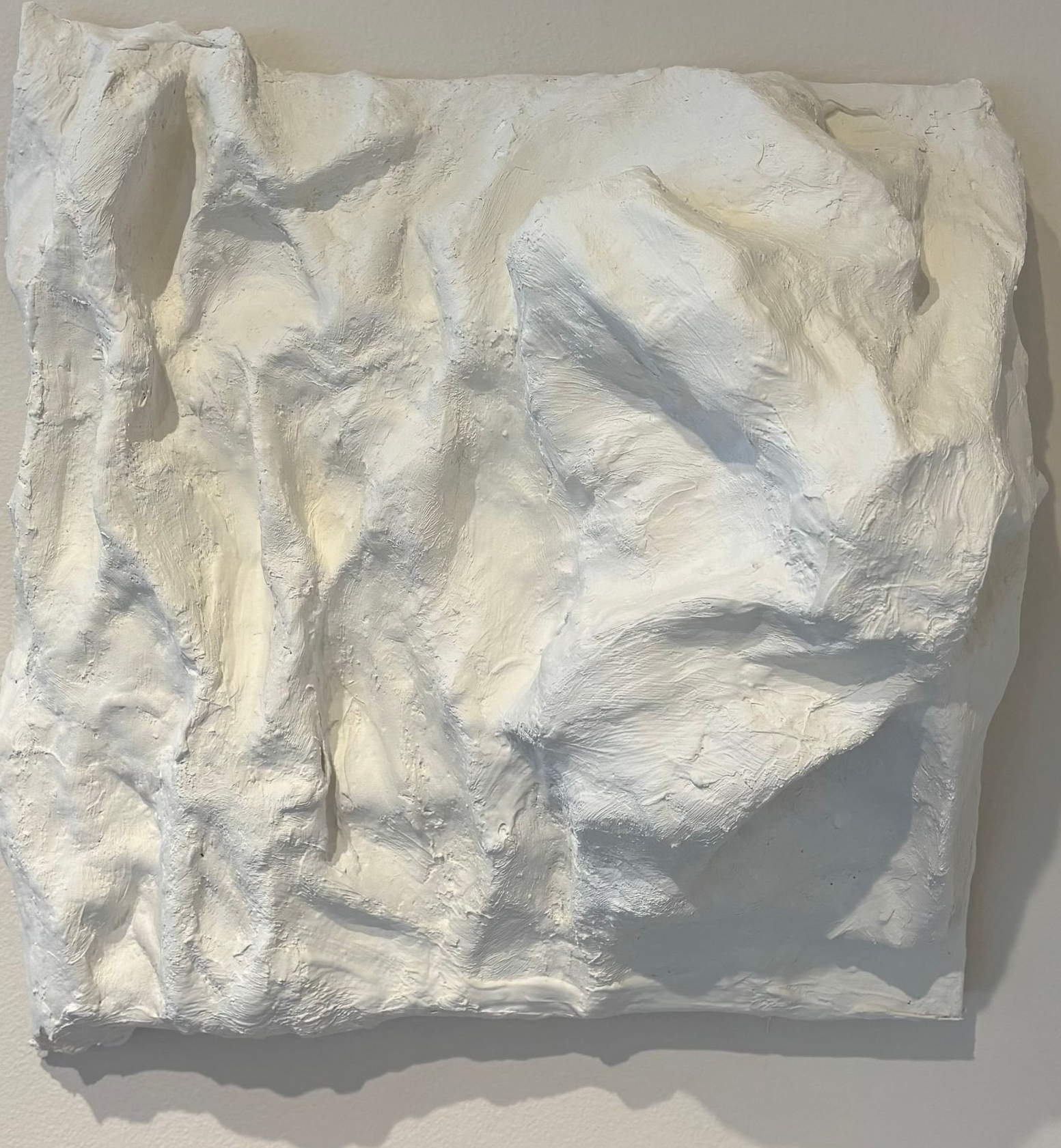 Crumpled white textured fabric or paper square on a light background