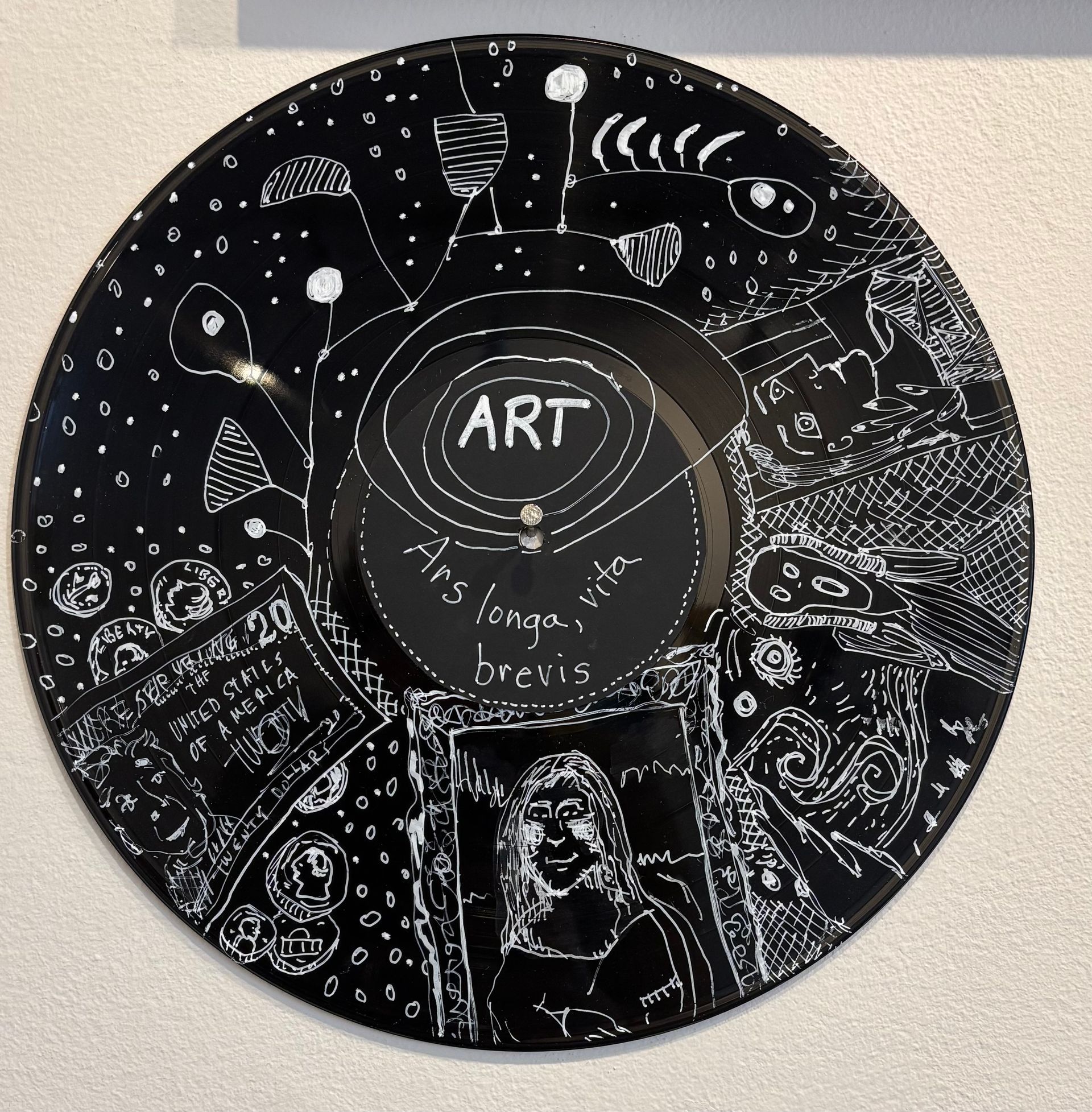 Black circular wall art with white doodles and “ART” in the center on a light wall