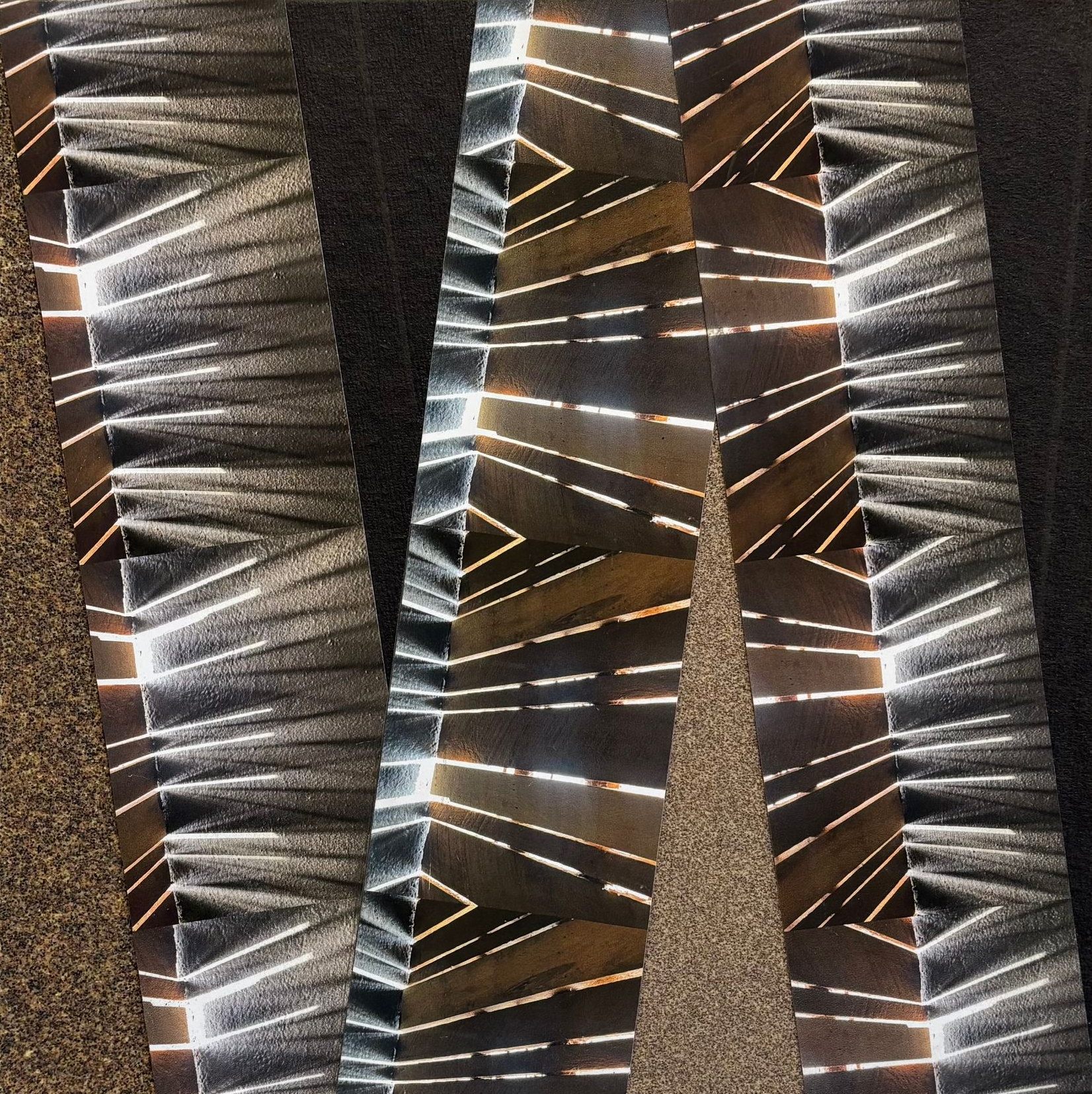 Abstract close-up of metallic, striped fabric with black, silver, and brown geometric patterns