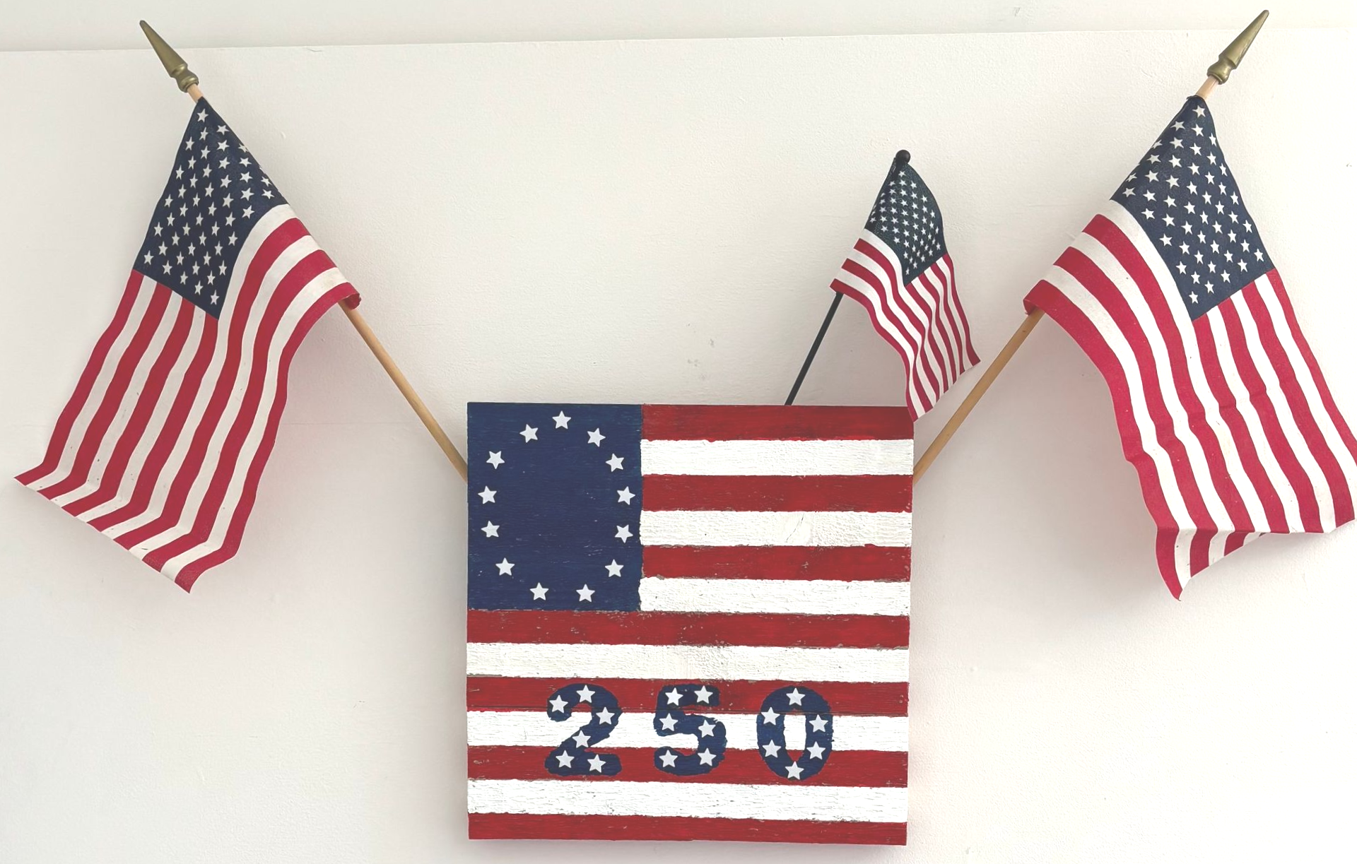 Patriotic wall sign with three American flags and the numbers 250 in red, white, and blue