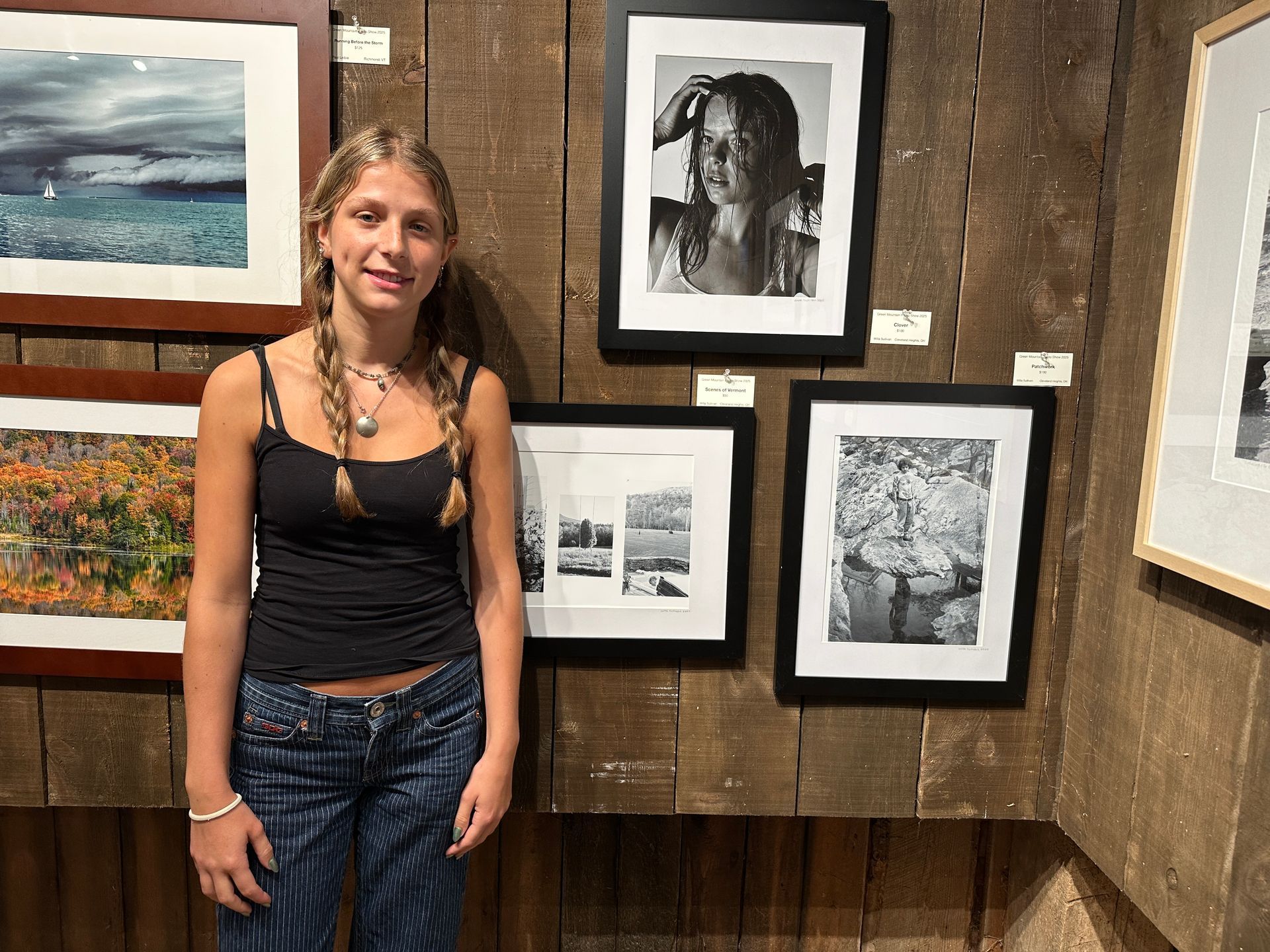 Woman standing in an art gallery beside framed photographs on a wooden wall