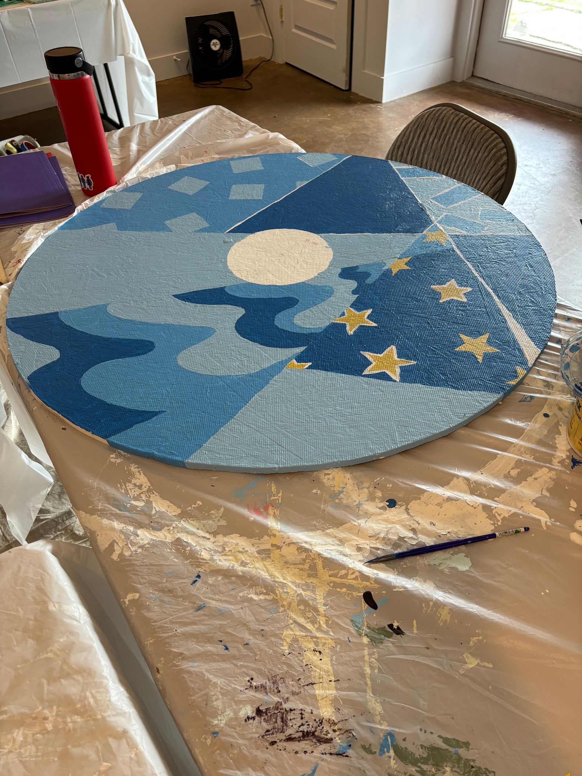 Blue moon-and-stars craft circle on a plastic-covered table in a dining room