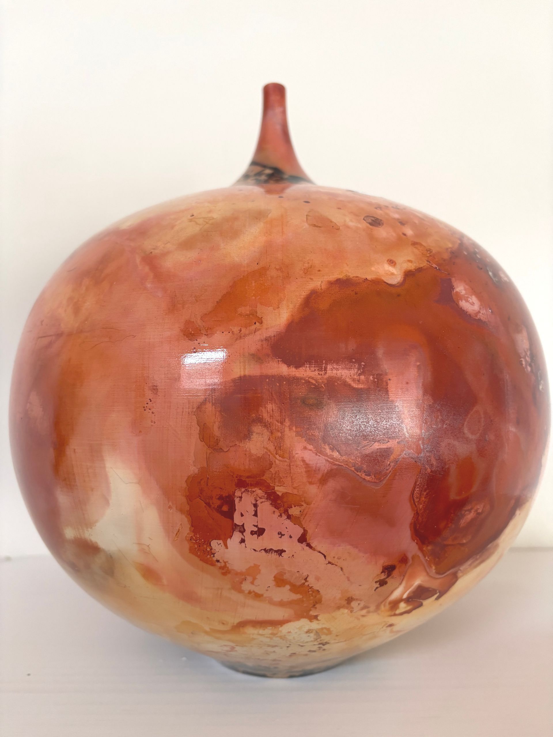Glossy round red-brown ceramic vase with a narrow neck on a plain white background