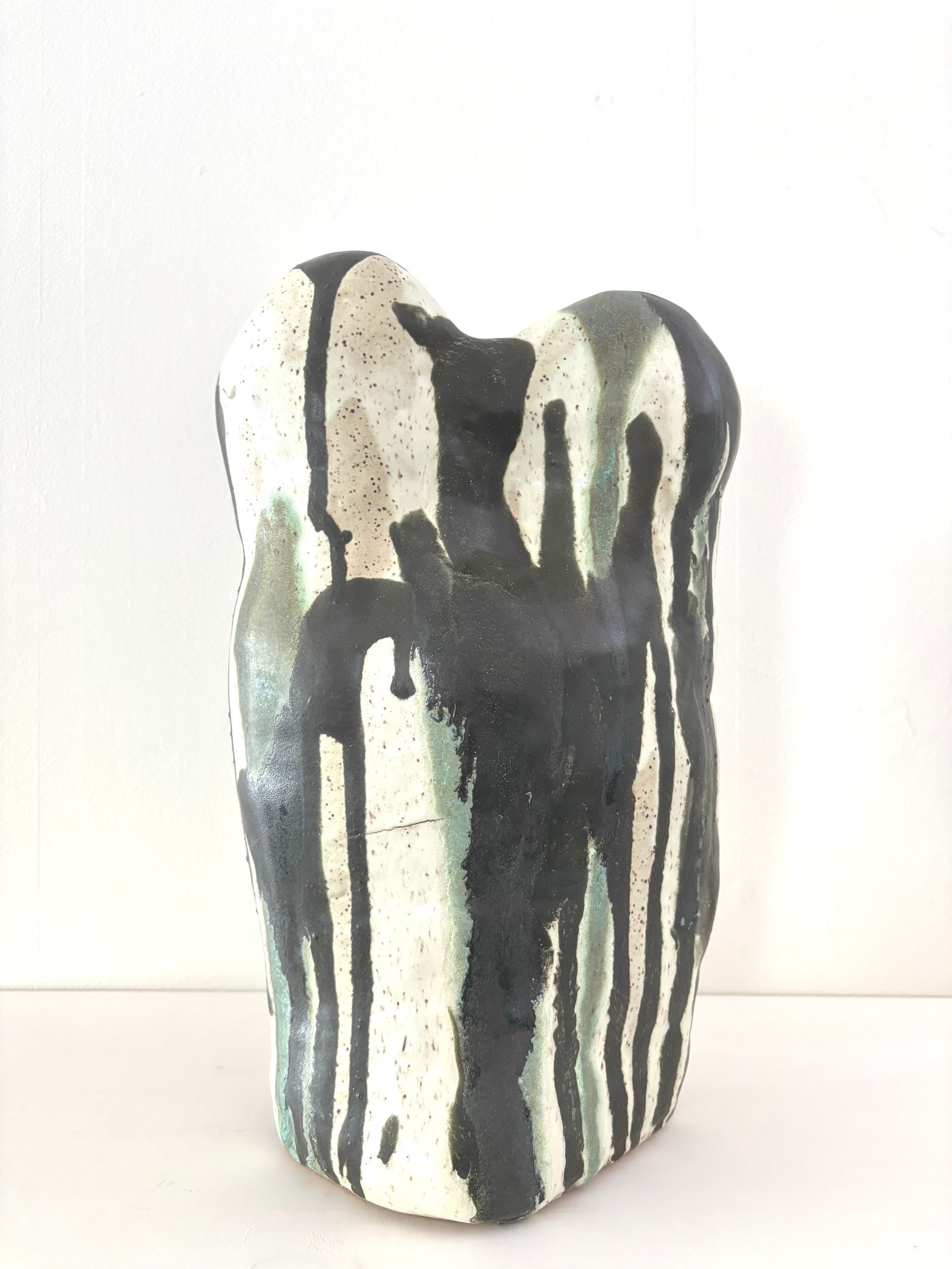 Abstract ceramic vase with black and white dripped glaze on a white background