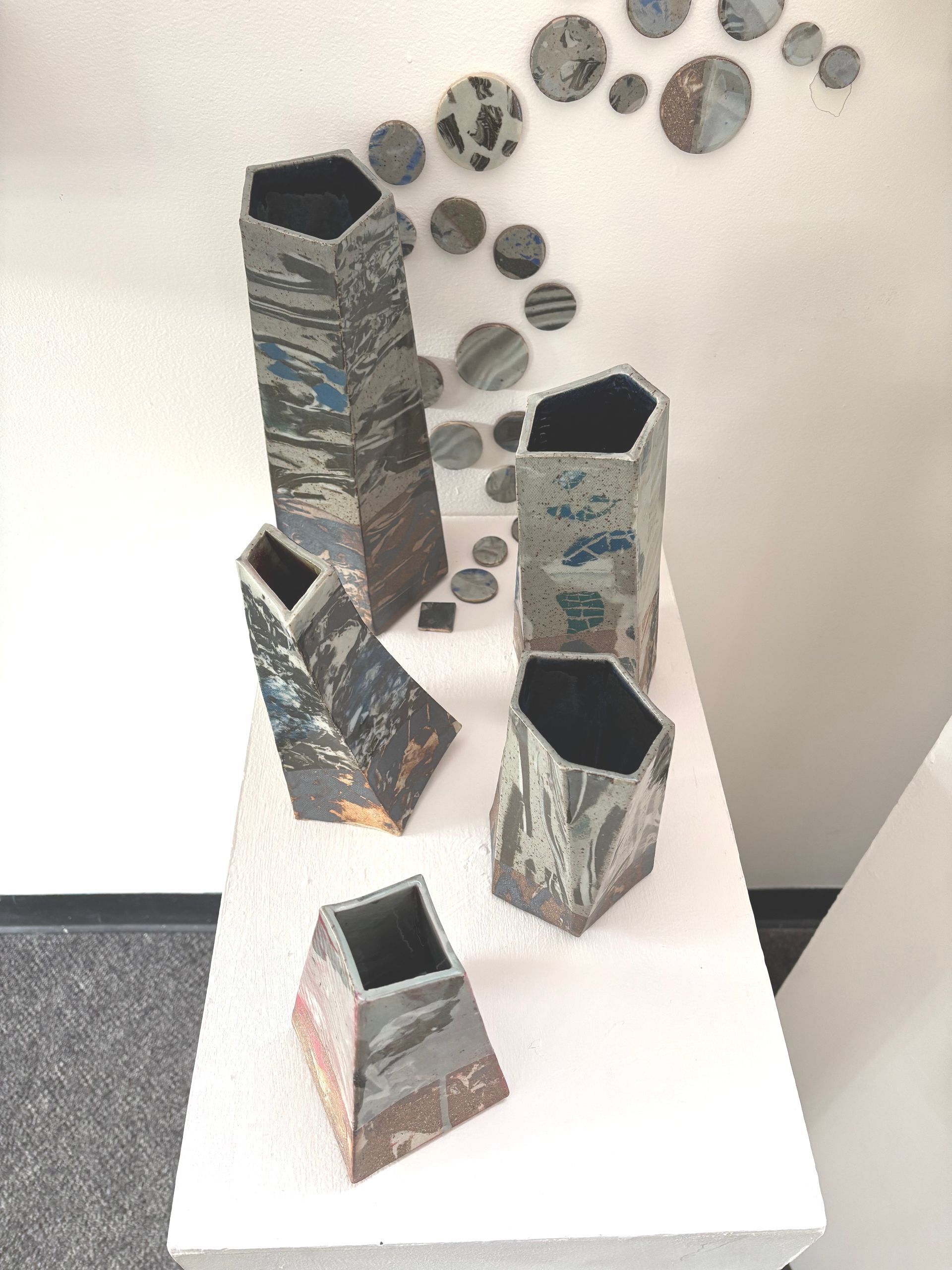 Abstract painted tower sculptures on a white table, with circular wall art in the background