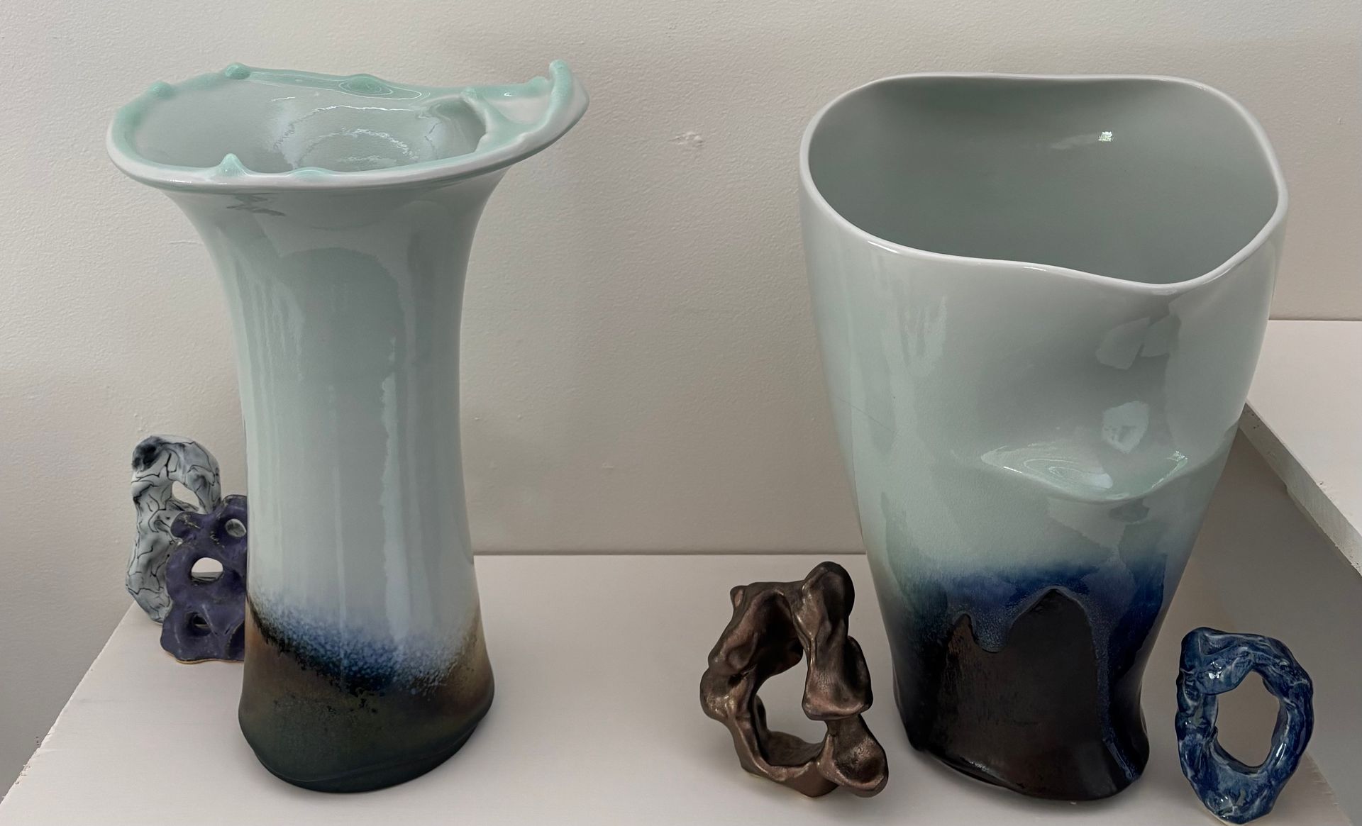 Two blue-and-white ceramic vases on a white surface, with small decorative stones beside them.
