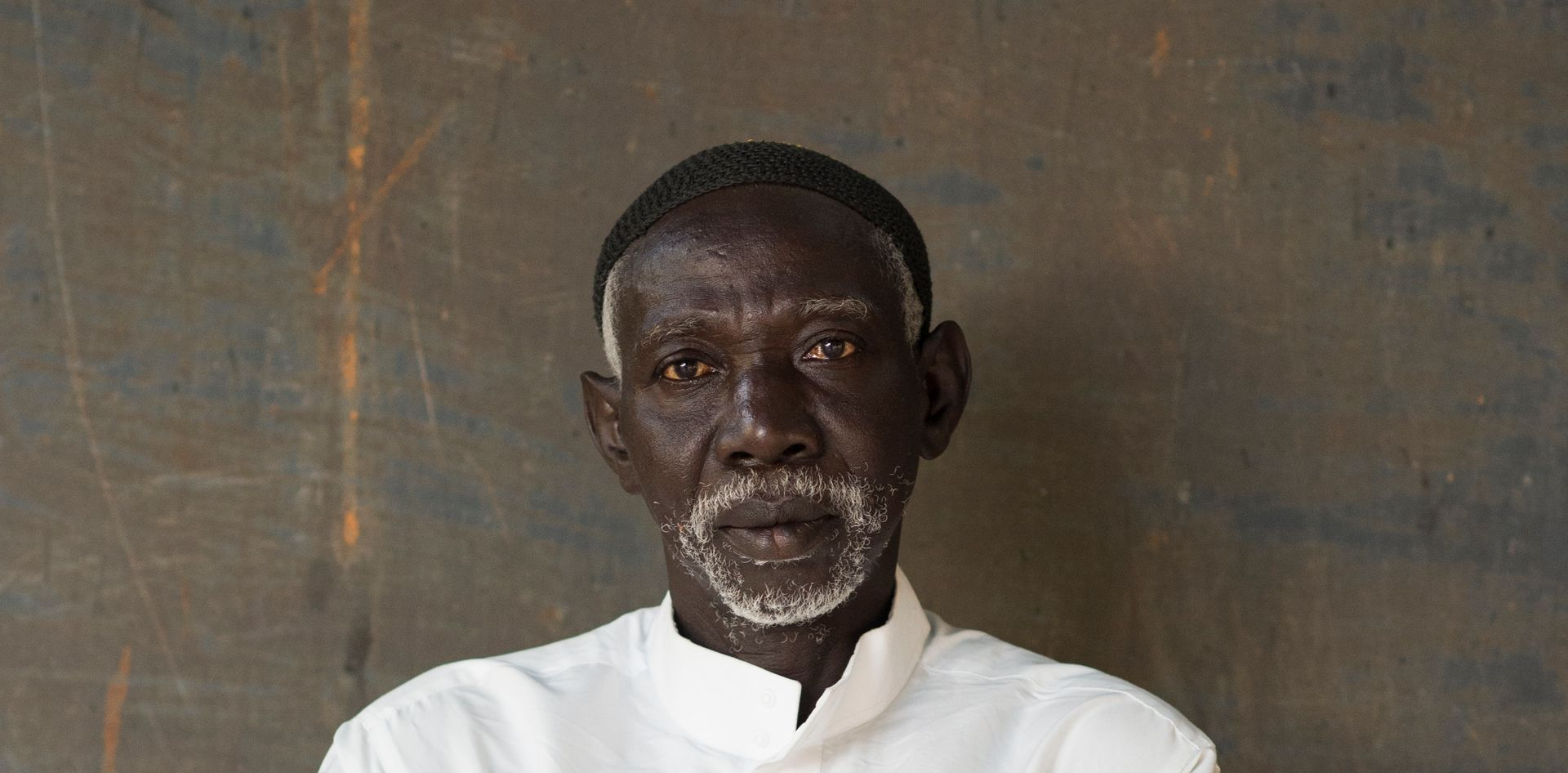 Portrait of a man in a white shirt against a dark, textured background
