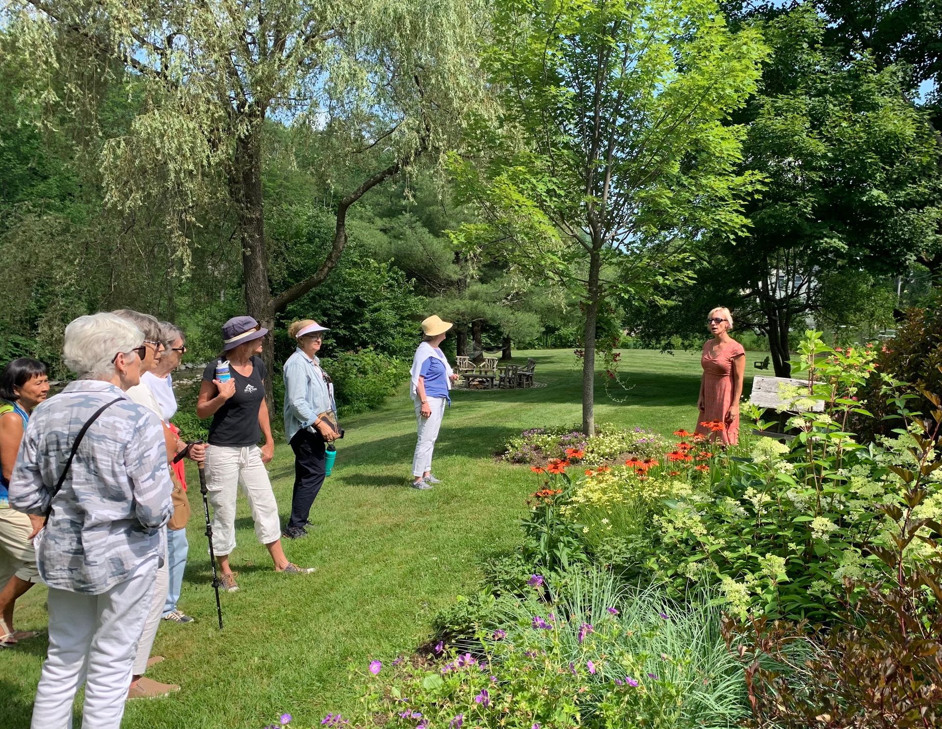 Group of people listening to a guide in a lush garden with colorful flowers and trees
