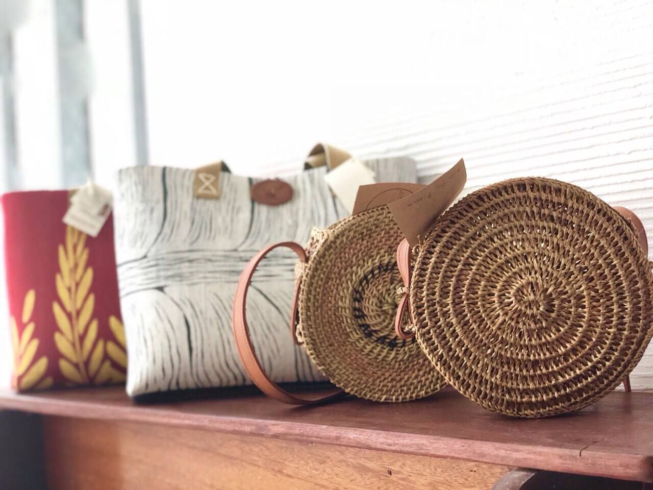Handcrafted rattan and fabric bags displayed on wooden shelf at Hue Hotel