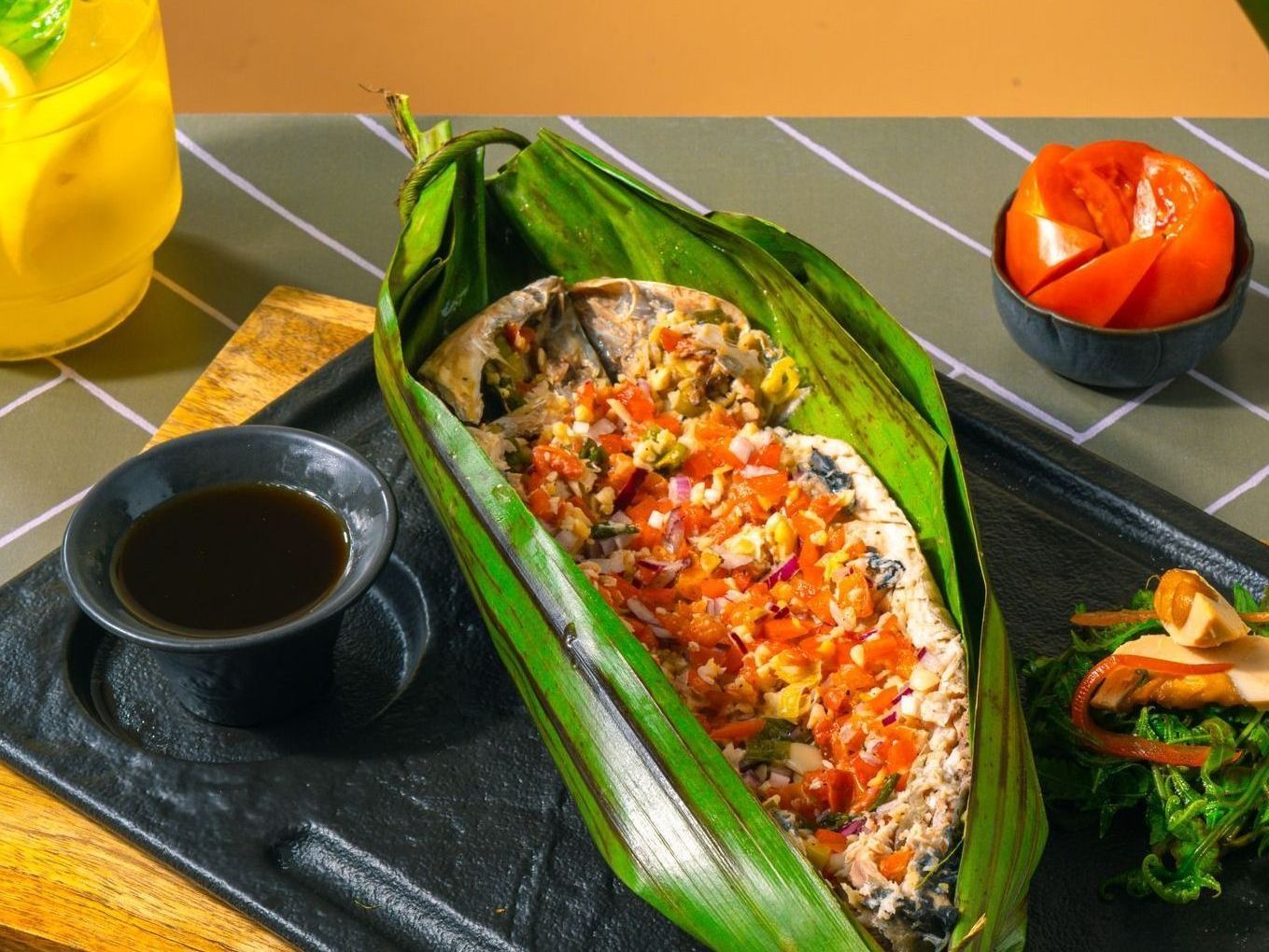 Seafood wrapped in a banana leaf on a table.