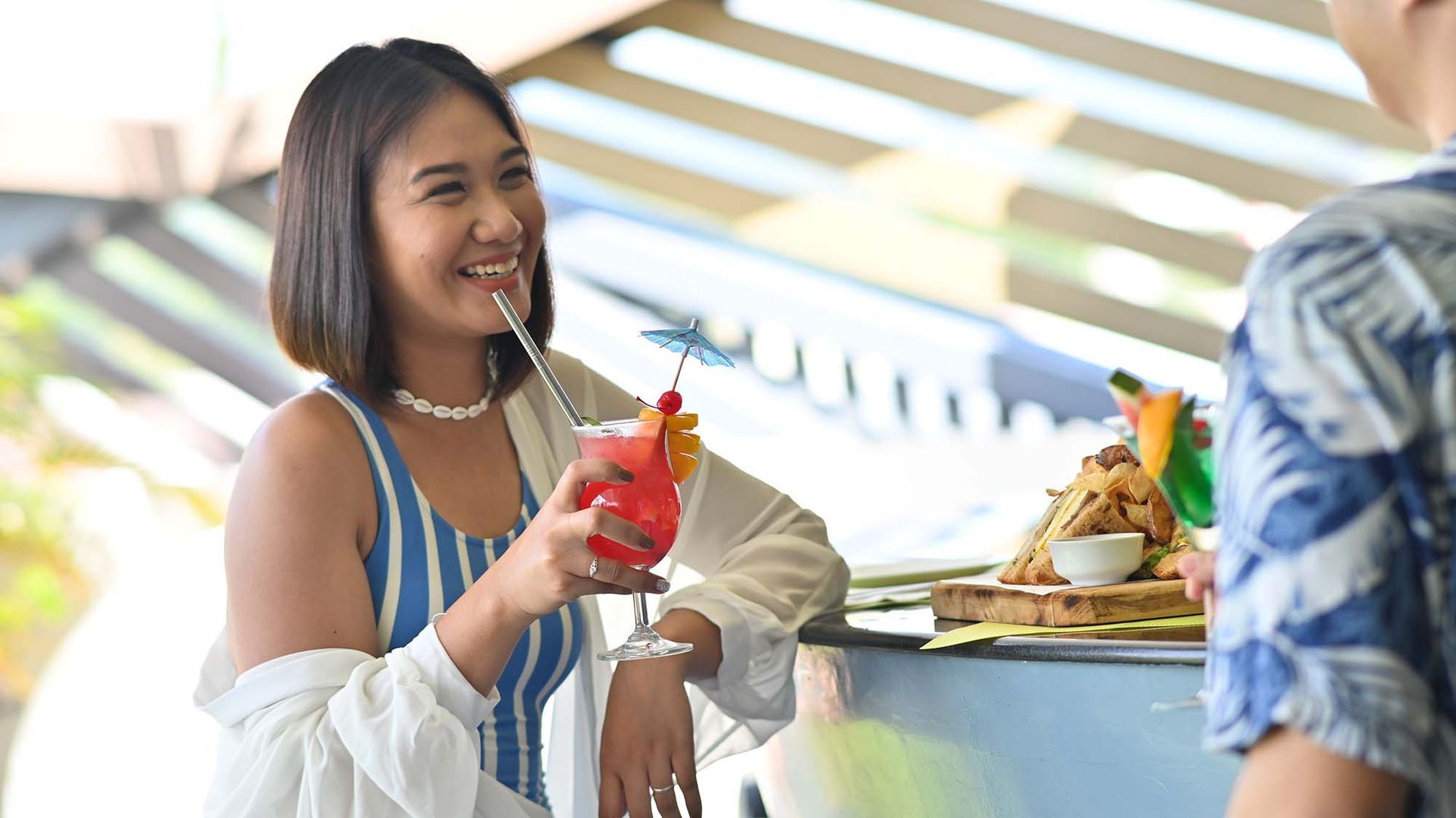 Guest enjoying refreshing cocktails and food at Hue - Puerto Princesa restaurant's outdoor dining area with natural lighting.