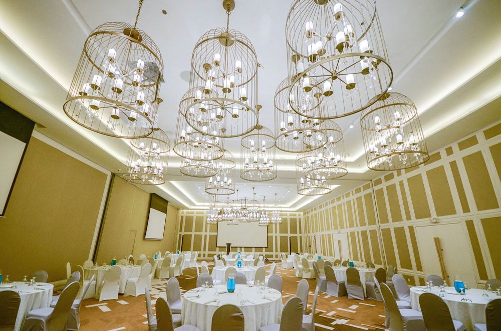 Elegant ballroom at best Puerto Princesa hotel featuring birdcage chandeliers, white table settings, and modern gold accents