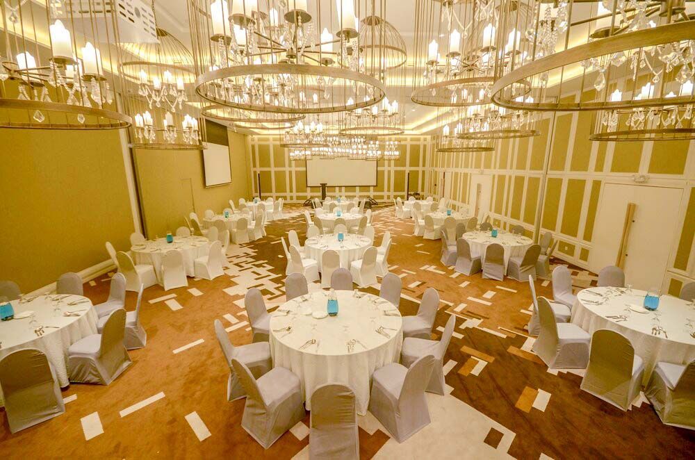 Spacious function hall at best Puerto Princesa hotel with dramatic lighting, round tables, and white chair covers