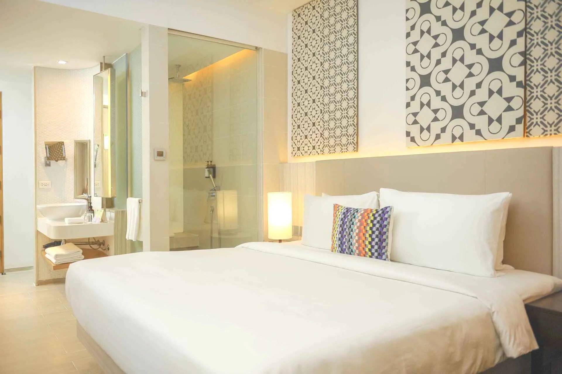 Hotel bedroom with a large bed, bathroom, and decorative wall panels.
