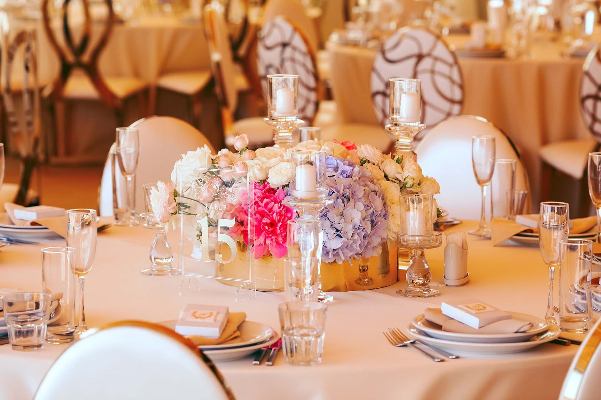 Elegant banquet table with floral centerpiece, candles, and white chairs in a warm, formal setting