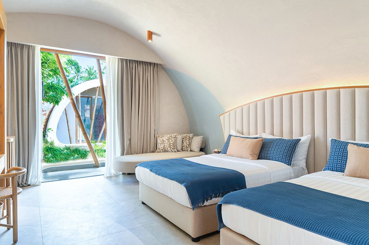 Bright twin bedroom with blue throws, arched ceiling, and garden view at Hu