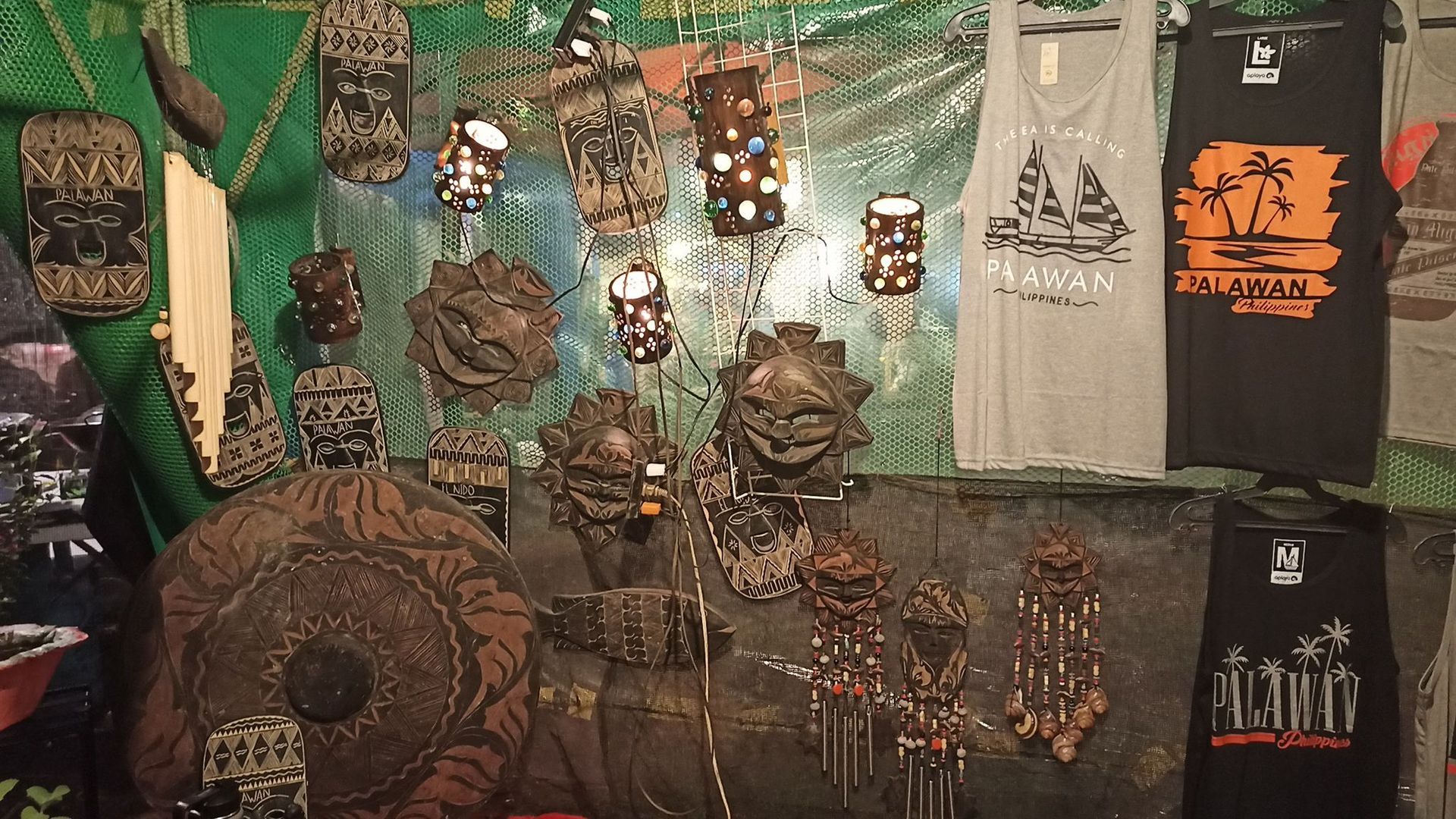 Palawan souvenir shop with carved wooden masks, lanterns, and printed shirt