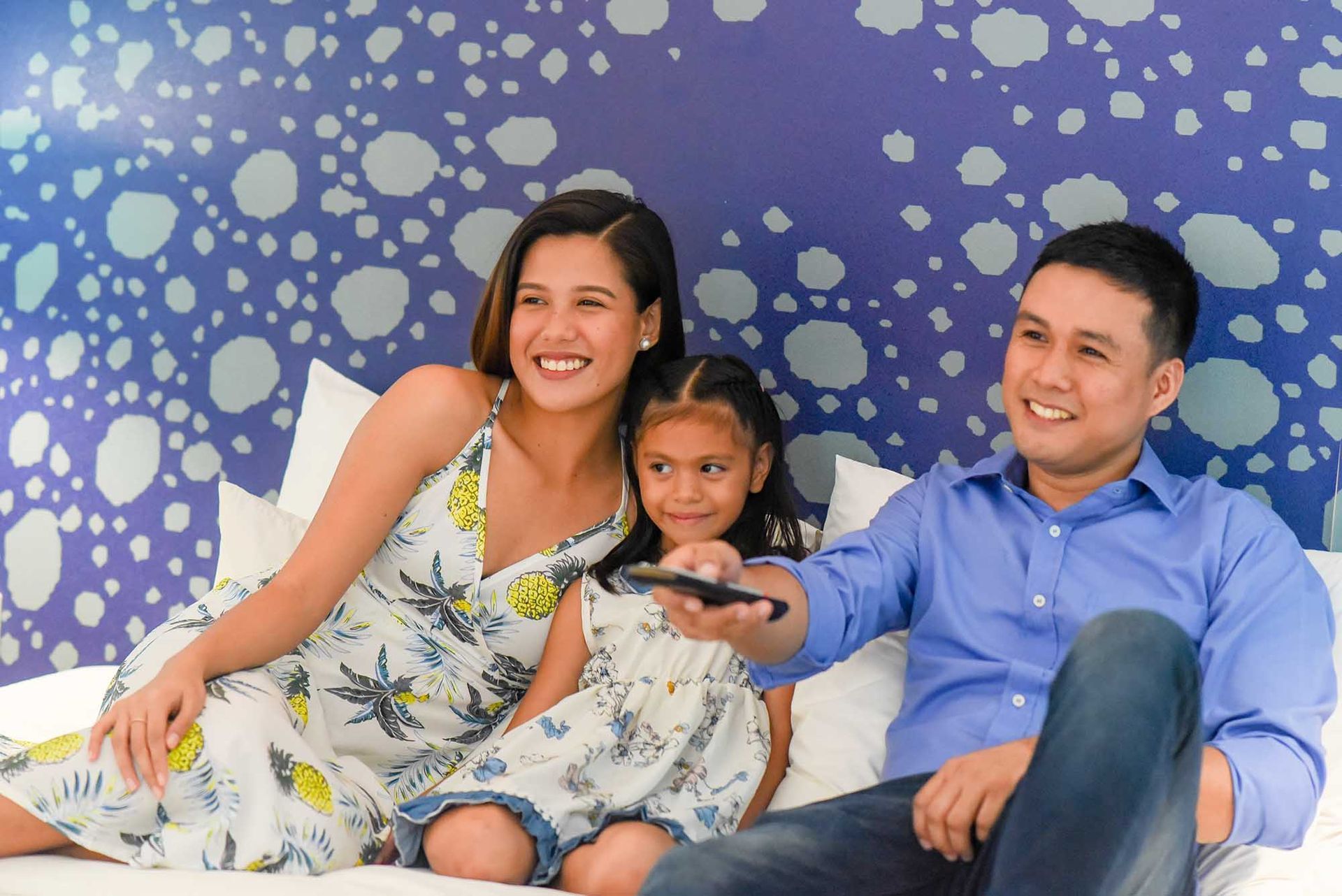 Family smiling on a couch against a blue bubble-patterned wall