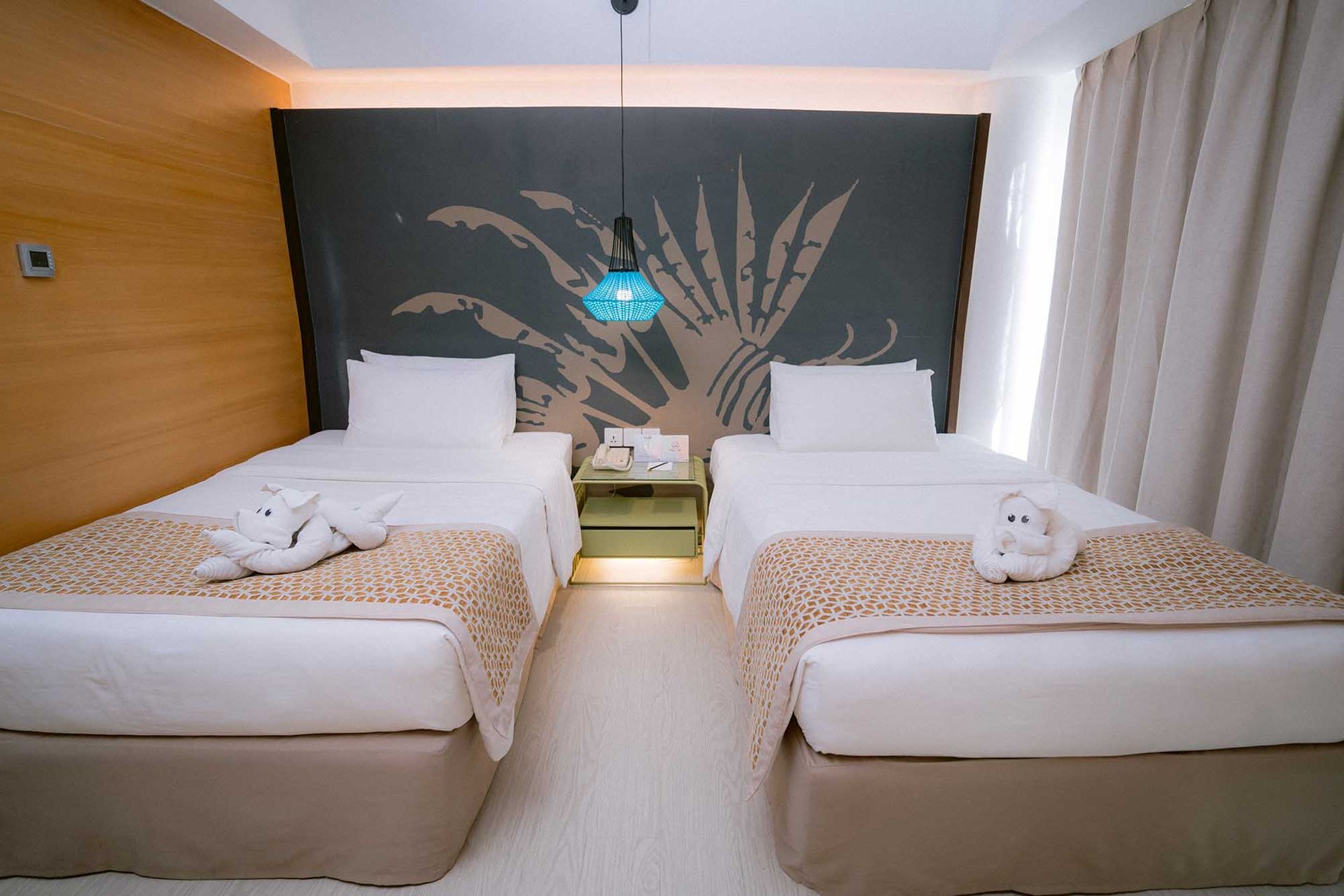Hotel room with two twin beds, white linens, wood paneling, and a patterned accent wall