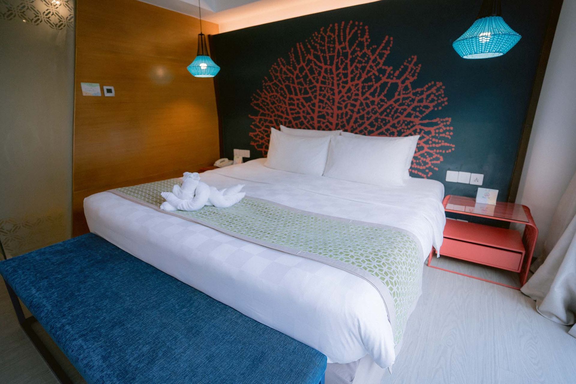 Family-friendly deluxe room in Boracay Station 2 with coral mural, turquoise lamps, and sage green bed runner