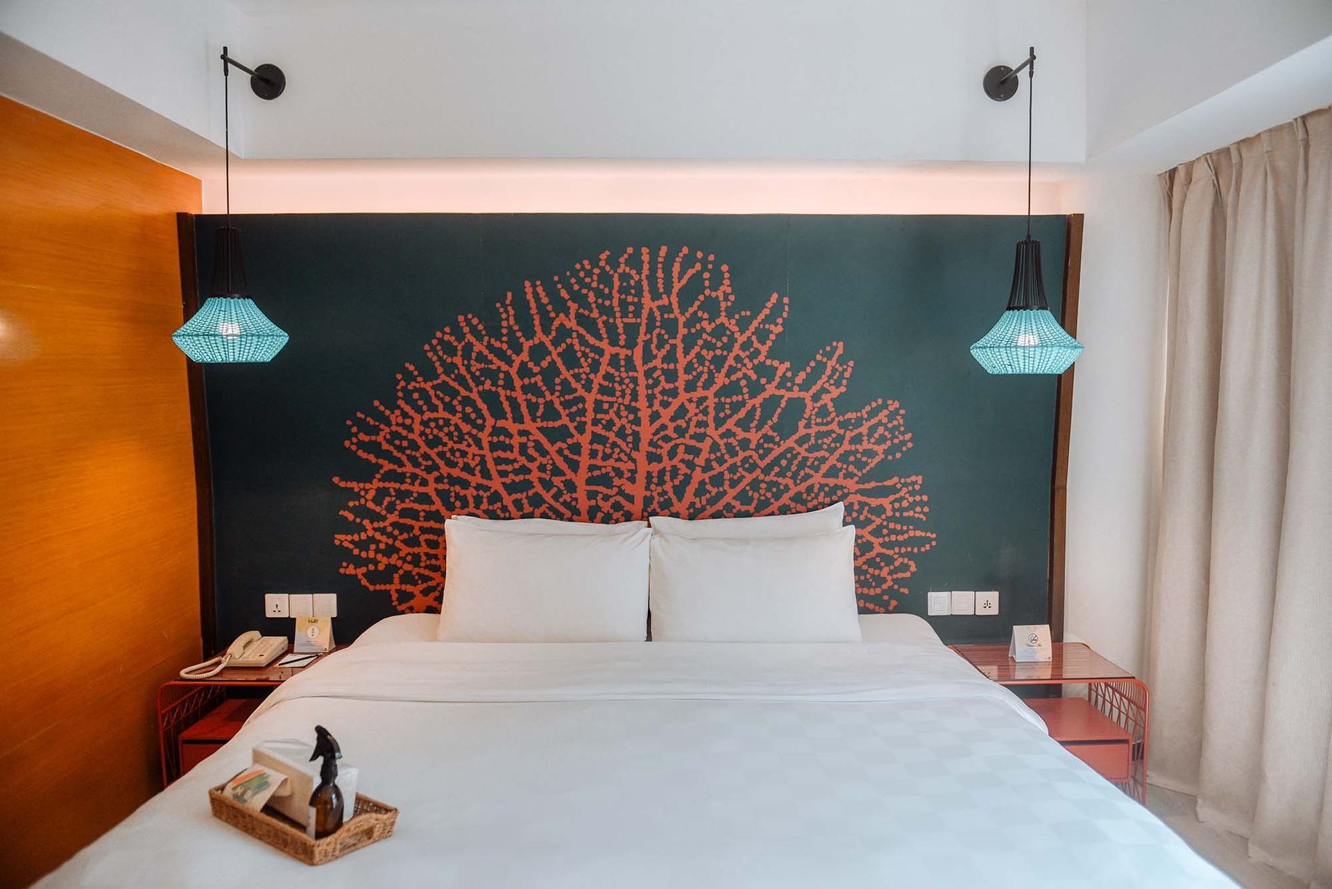Deluxe room at Boracay Station 2 hotel featuring coral-inspired wall art, turquoise pendant lamps, and white bedding
