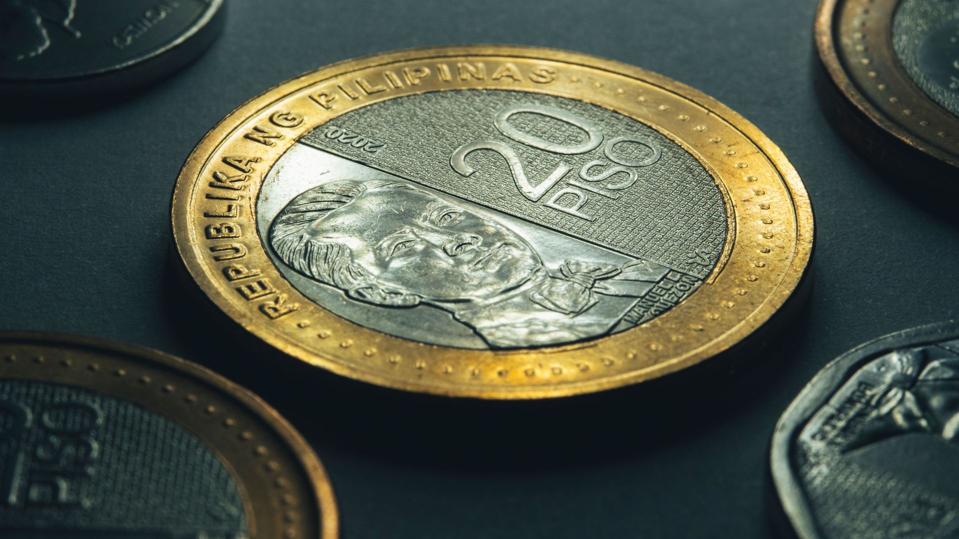 Close-up of a gold-toned 20-rand coin among other dark coins on a dark surface