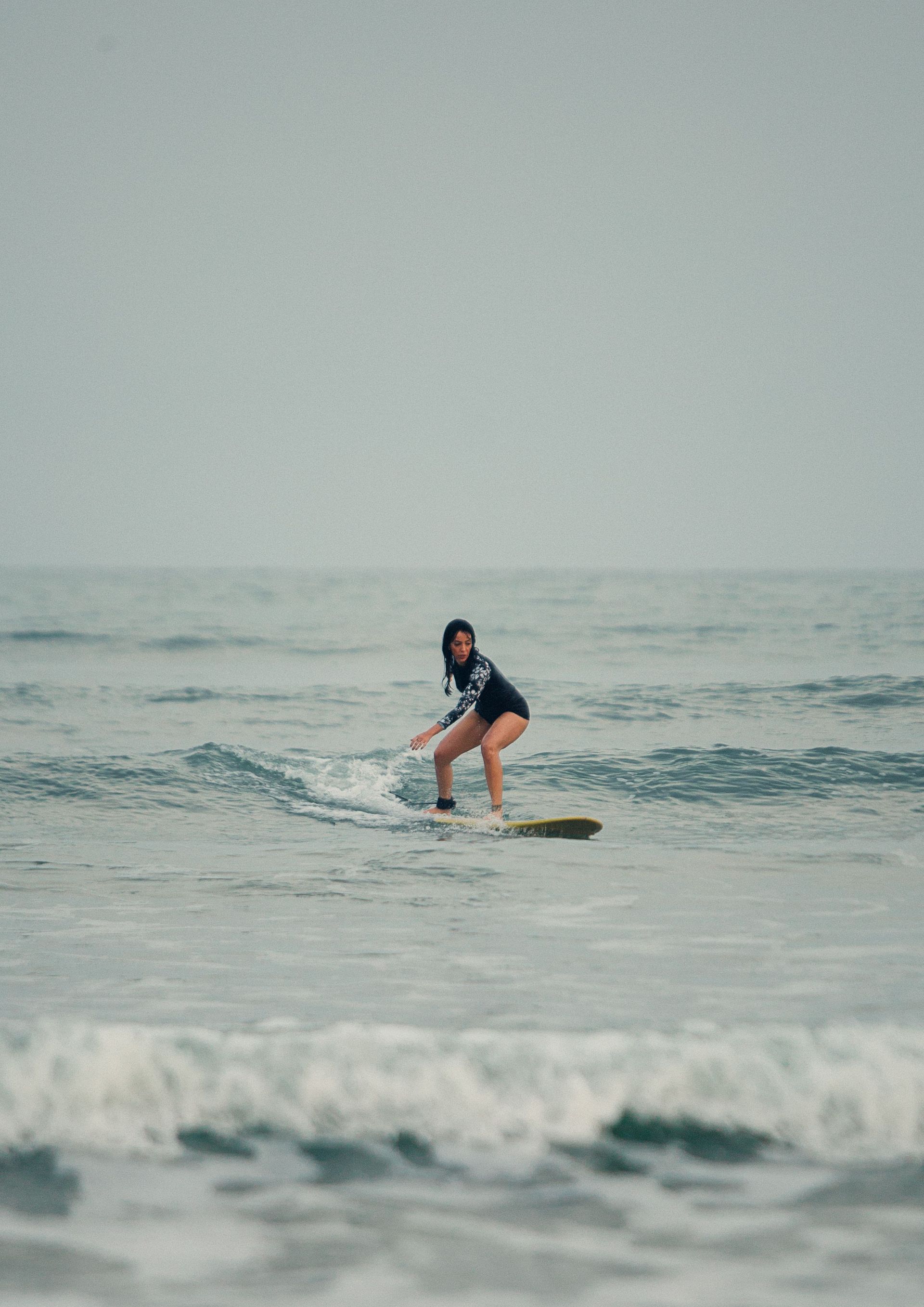 Person surfing on a small wave in the ocean under an overcast sky