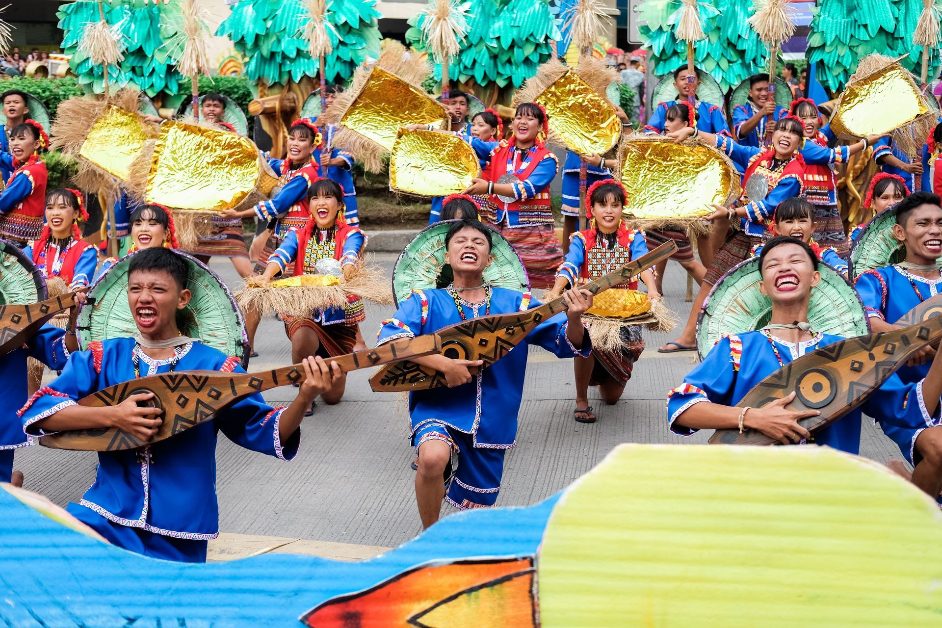 Colorful street dancers in blue costumes performing with wooden instruments in a festive parade
