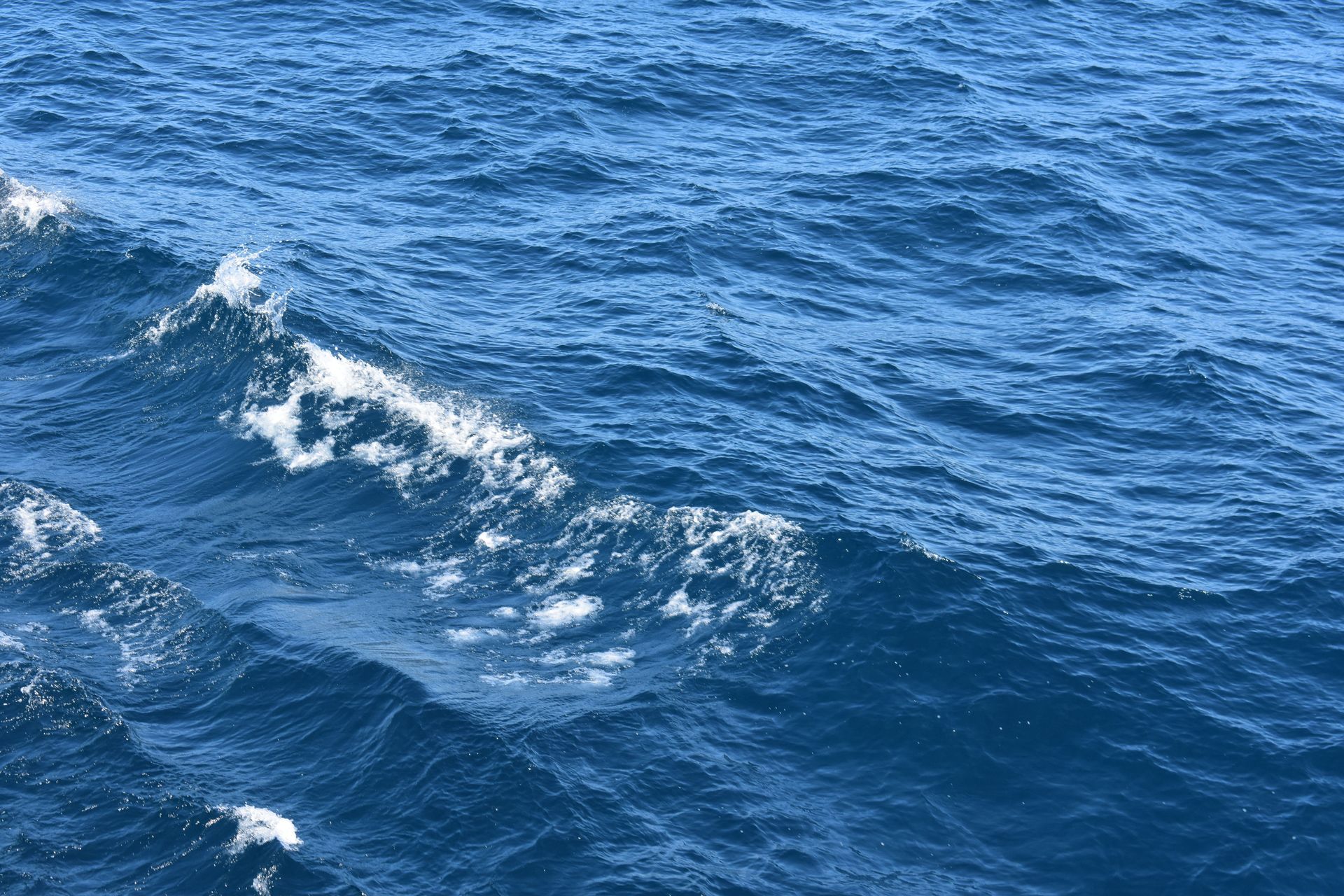 Blue ocean waves with white foam on the water surface