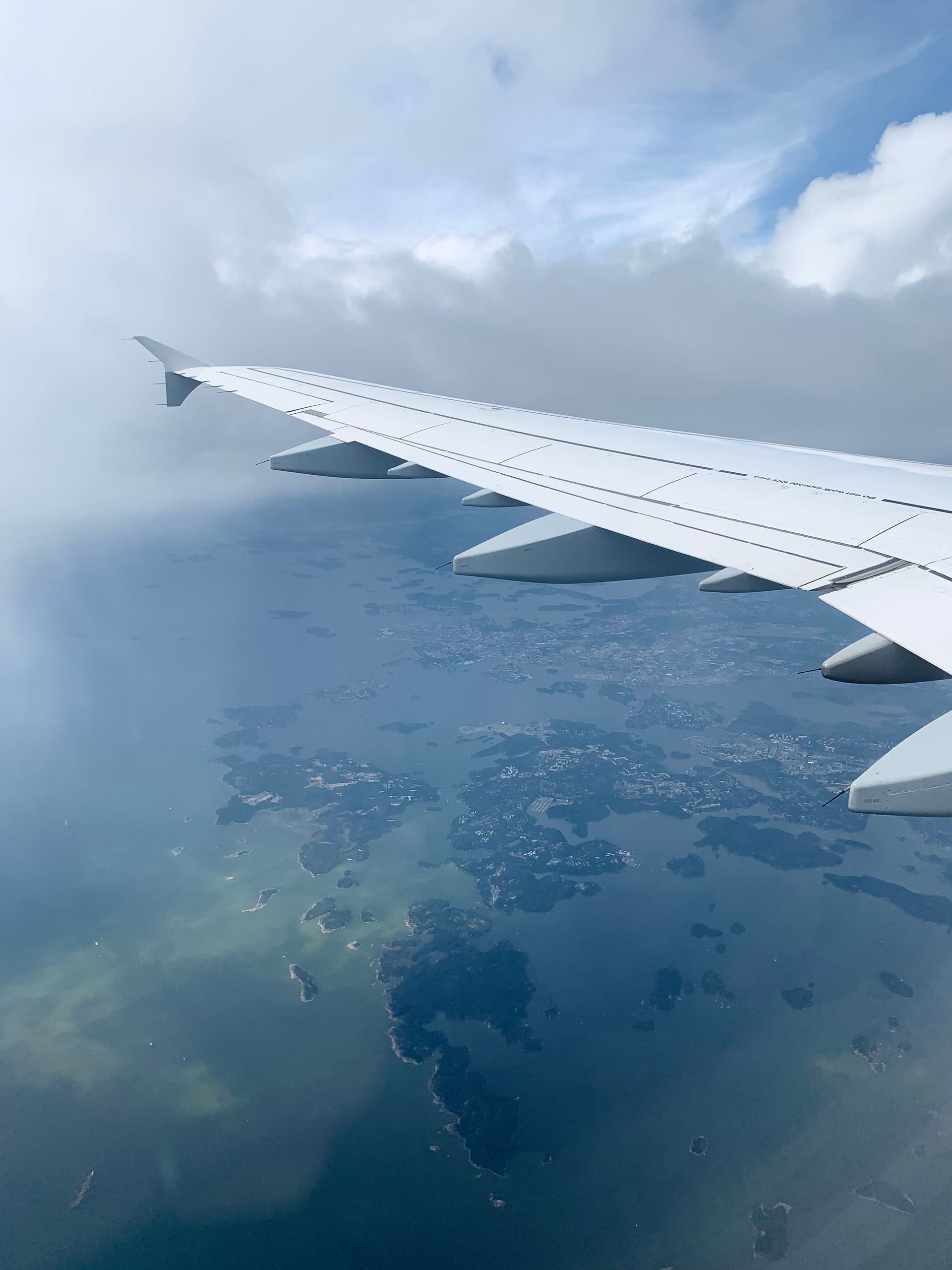 Airplane wing above clouds and patchwork land below
