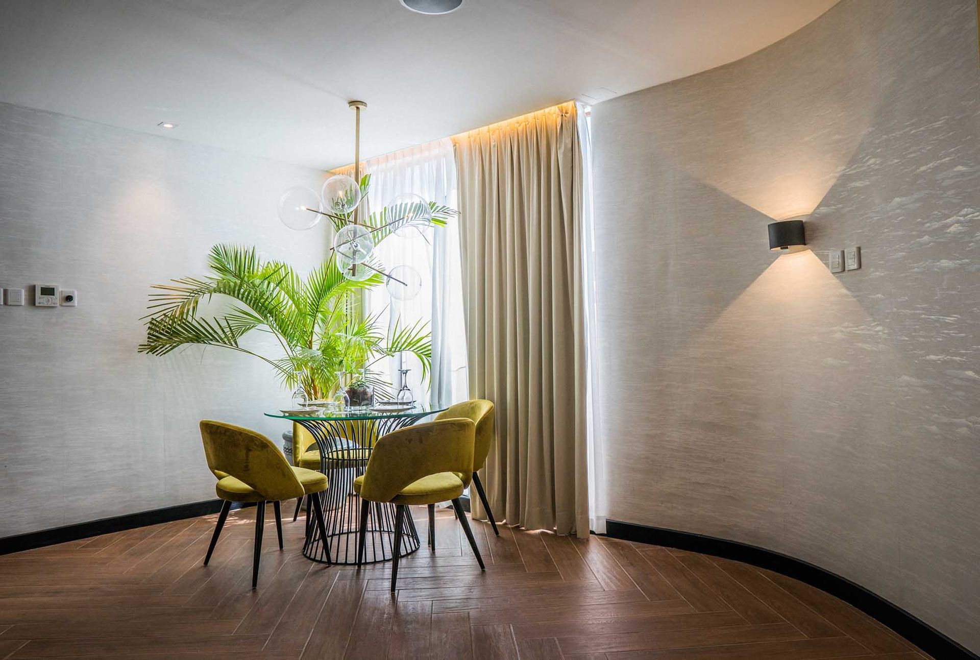 Dining nook in Spectrum Suite Boracay with velvet chairs, glass table, and tropical palm plants by window
