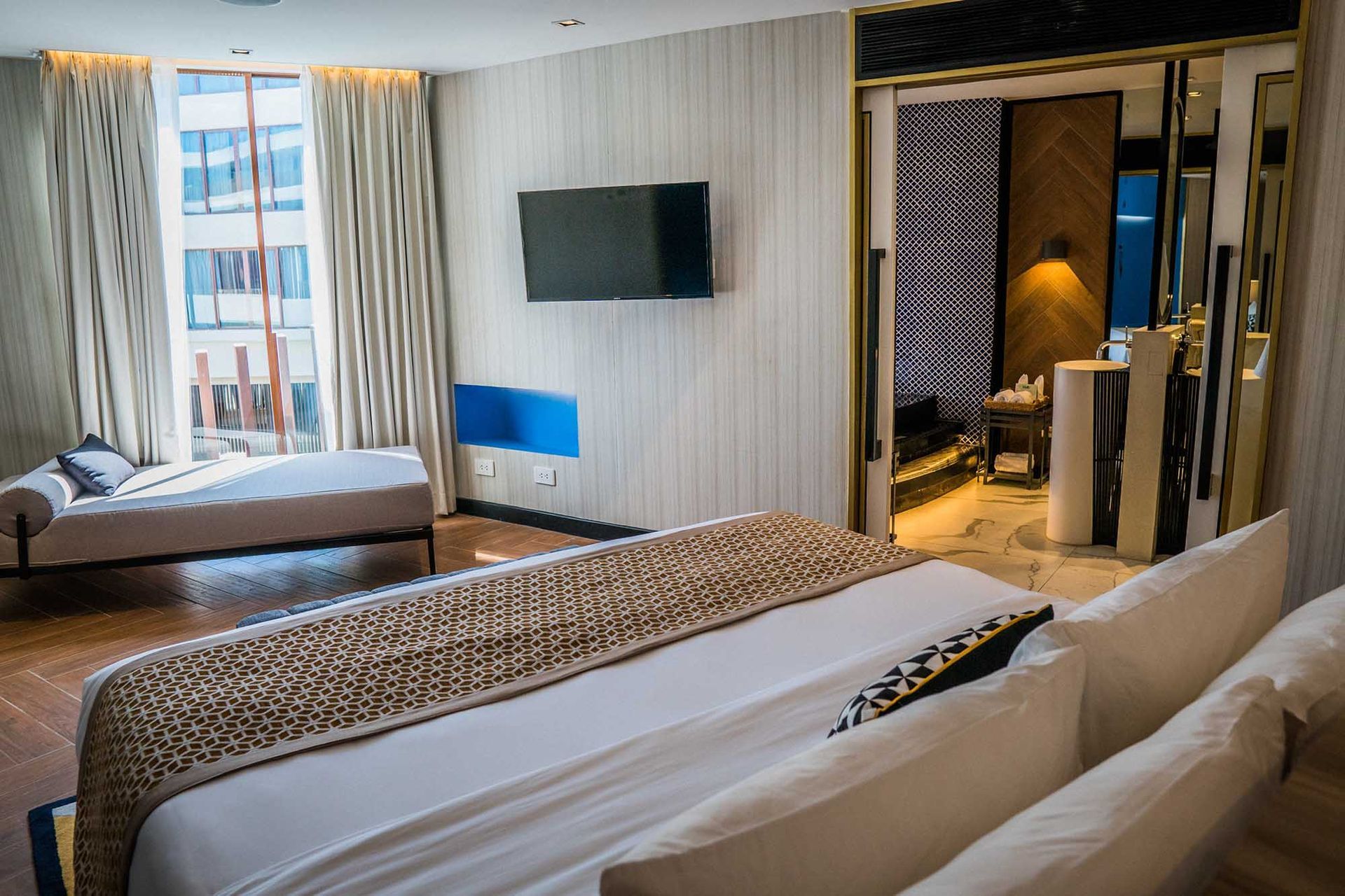 Spacious bedroom in Boracay Spectrum Suite with wall-mounted TV, geometric runner, and connecting dressing area