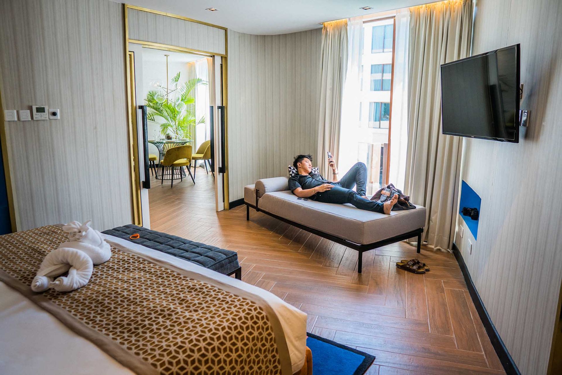 Stylish hotel room with purple mural, teal accents, and towel art at Hue Ho