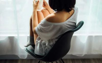 A woman is sitting in a chair holding a cup of coffee.