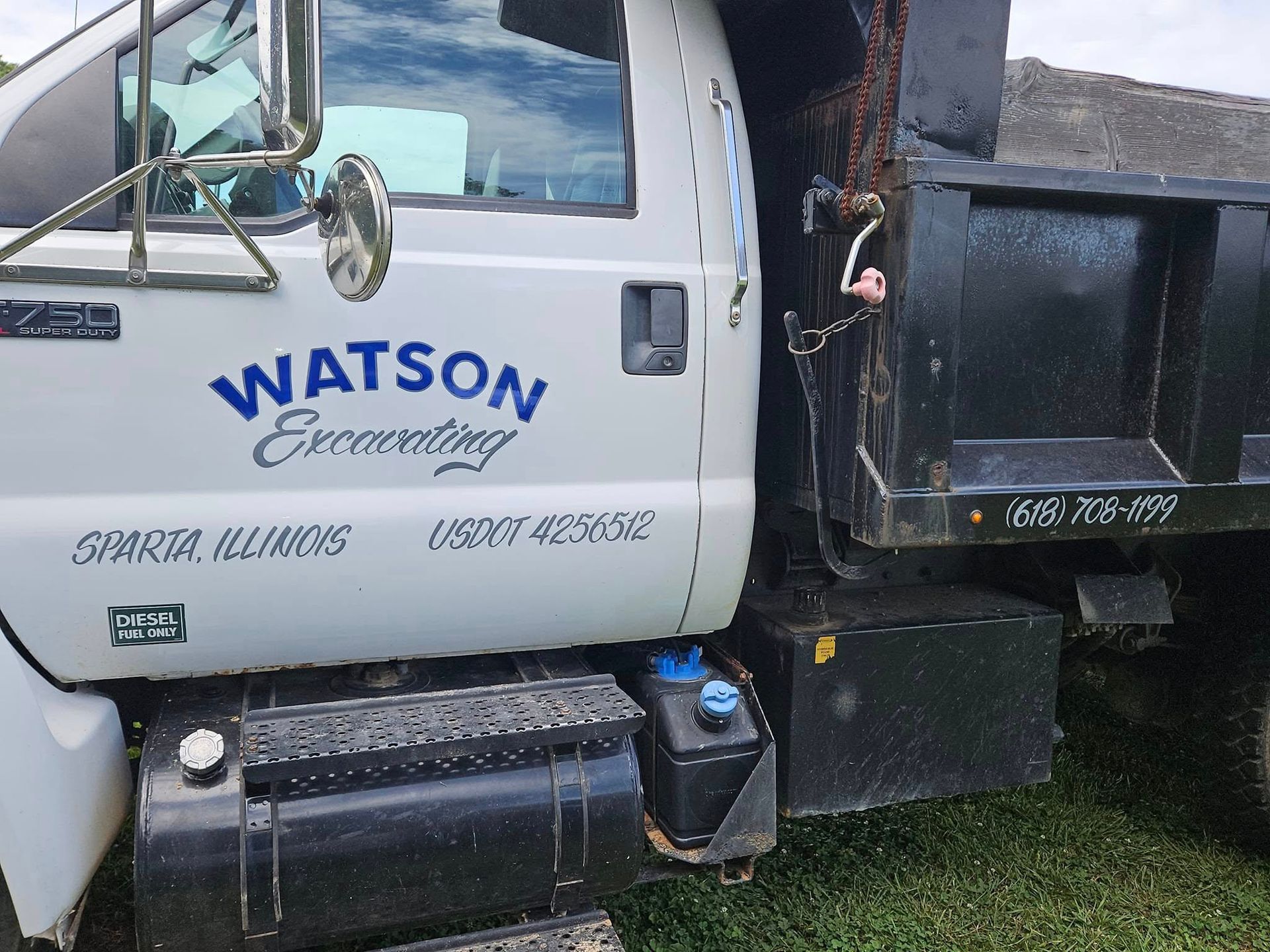 A side view of a white Watson Excavating dump truck parked on grass in Sparta, Illinois.